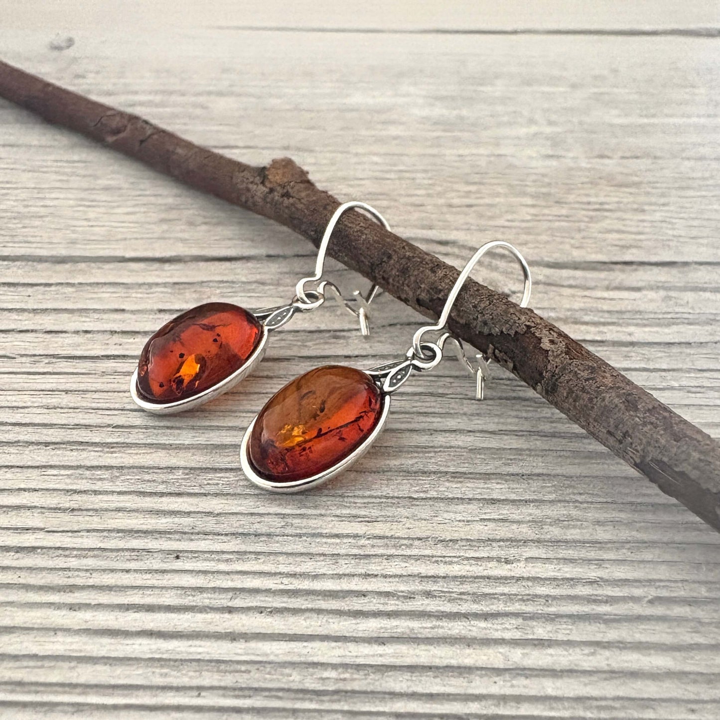 Amber earrings with silver hooks on a wooden surface