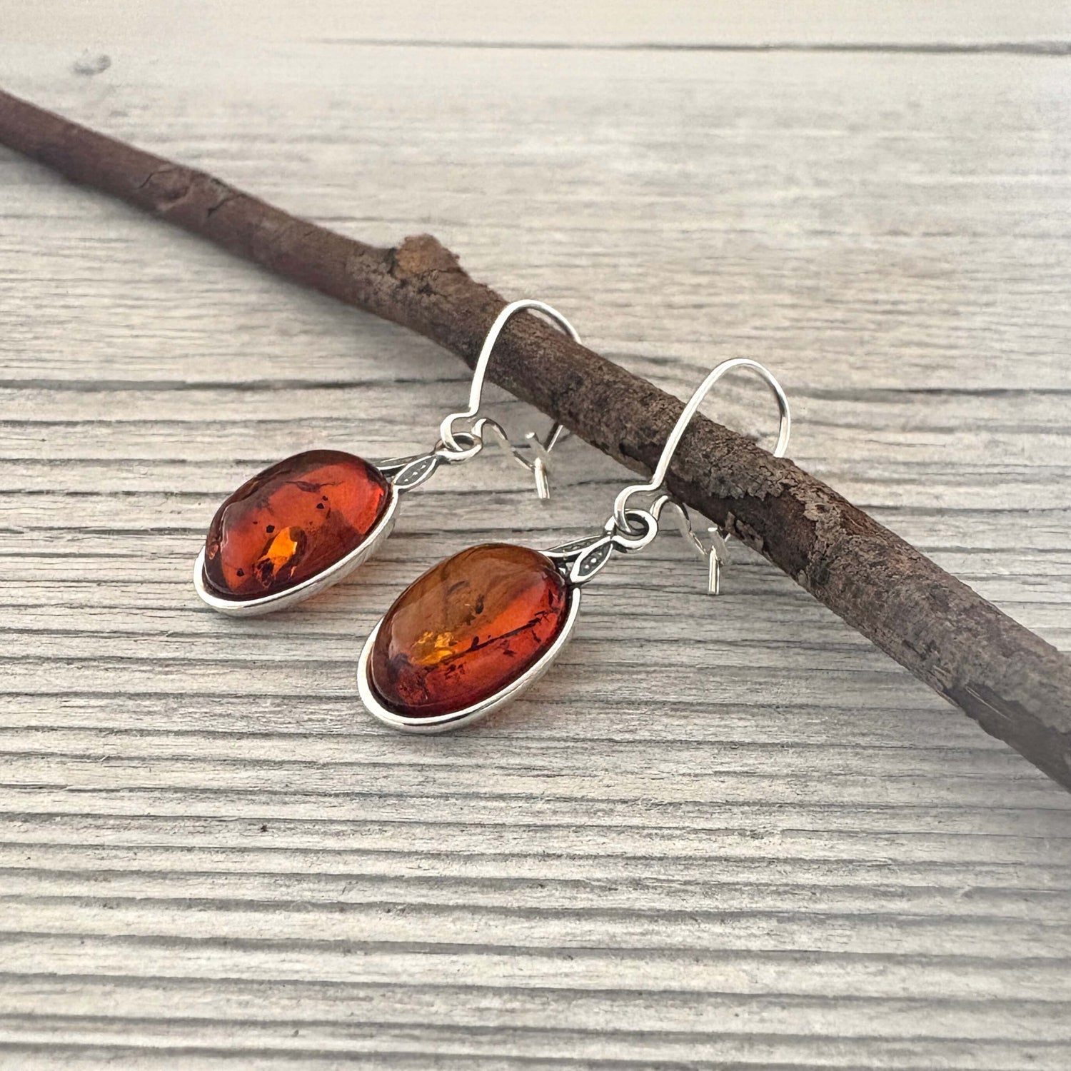 Amber earrings with silver hooks on a wooden surface