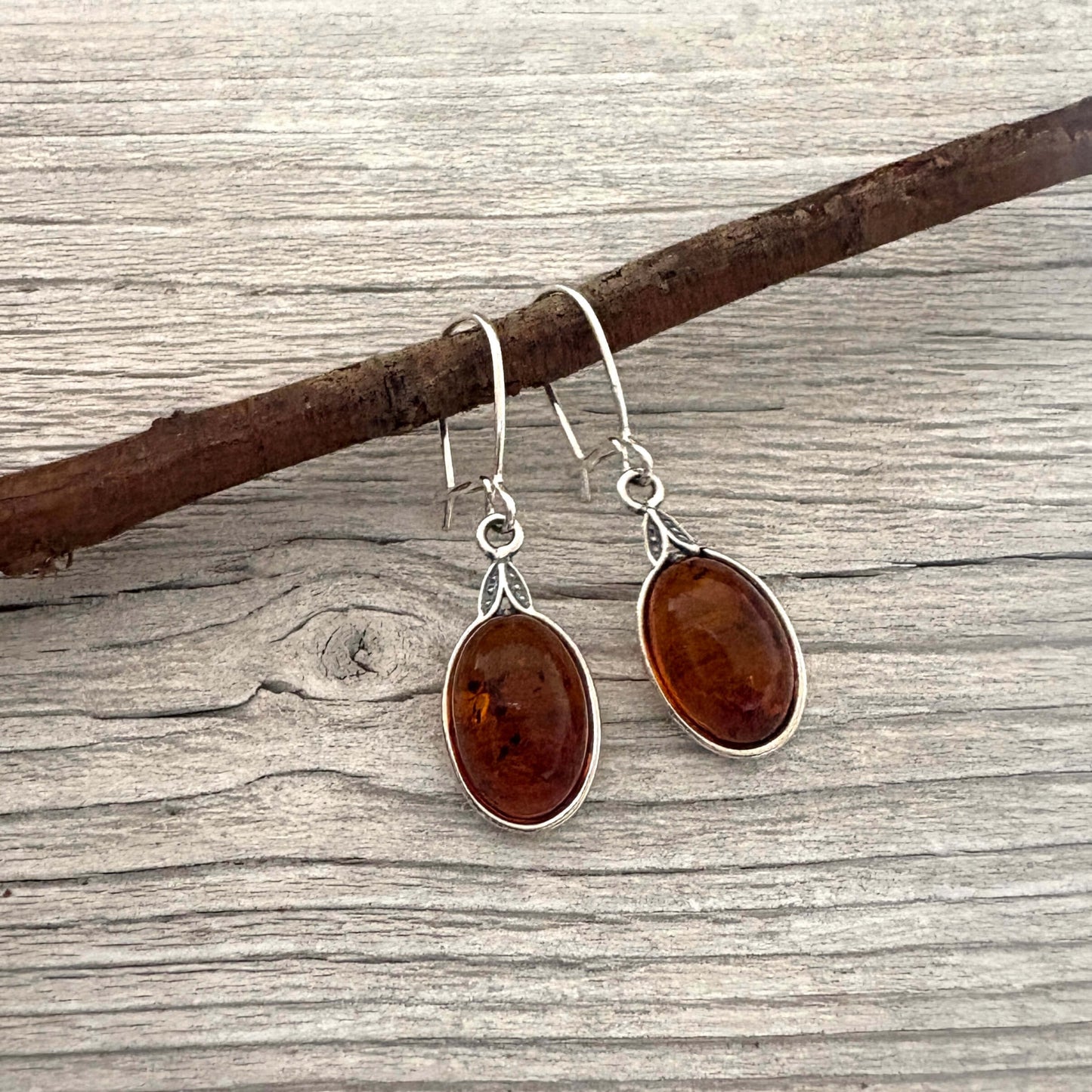 Pair of amber stone earrings on a wooden branch
