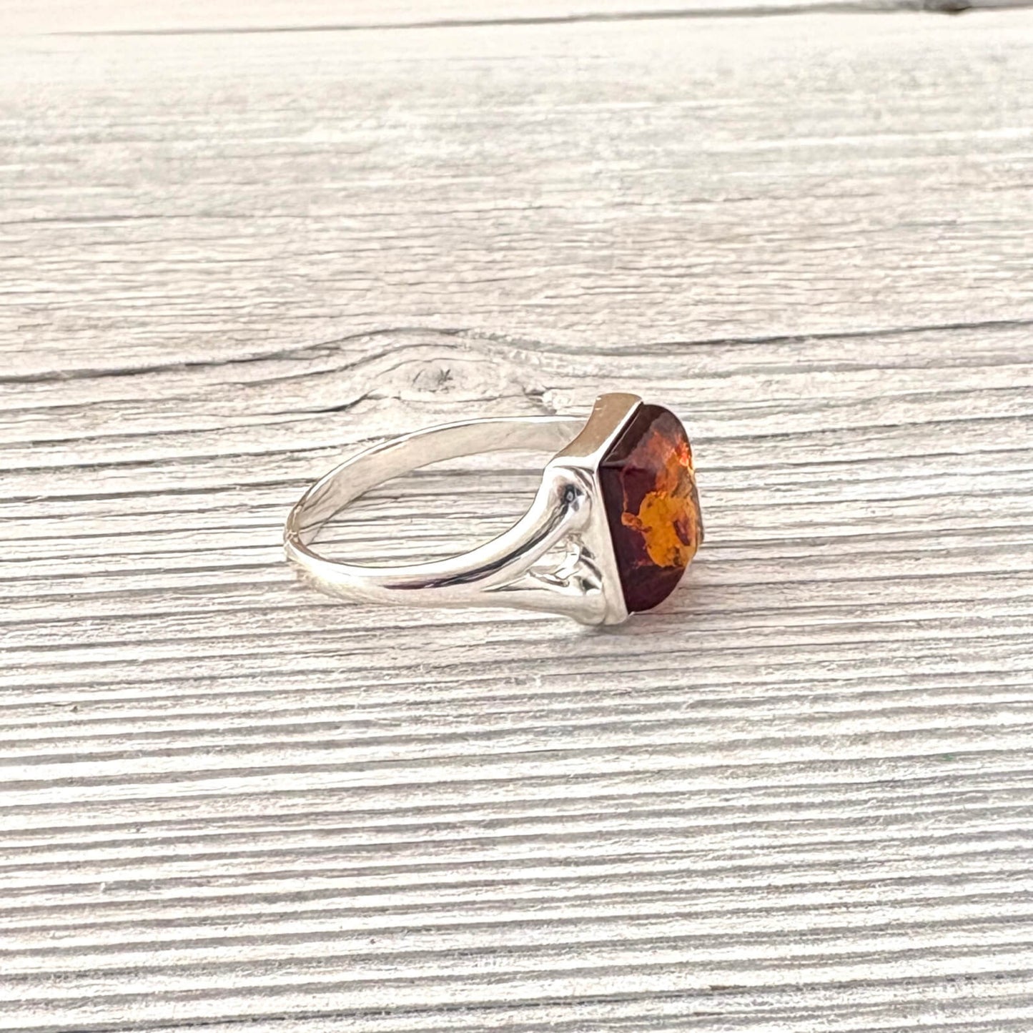 Silver ring with a amber stone on a wooden surface