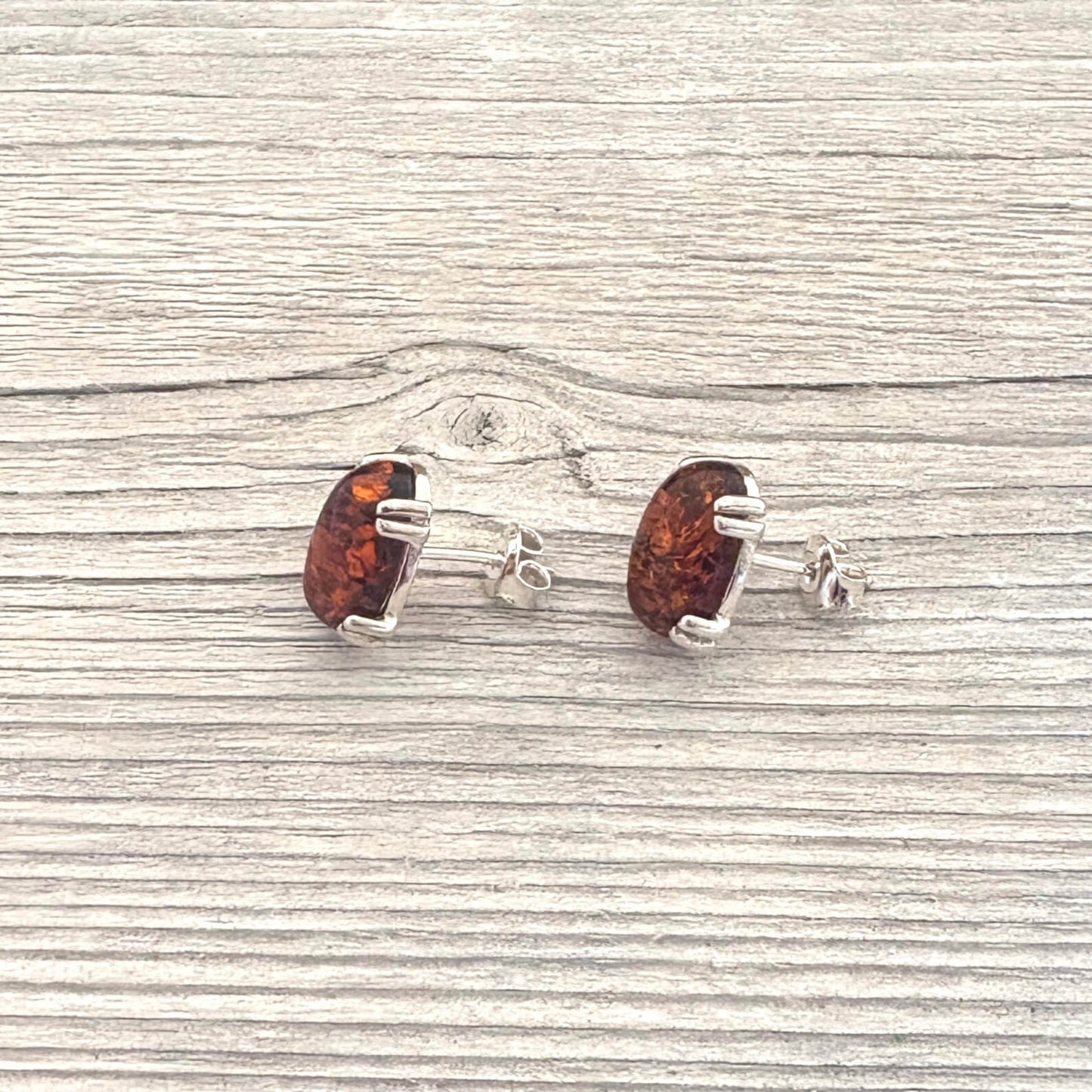 Pair of amber stud earrings on a wooden surface