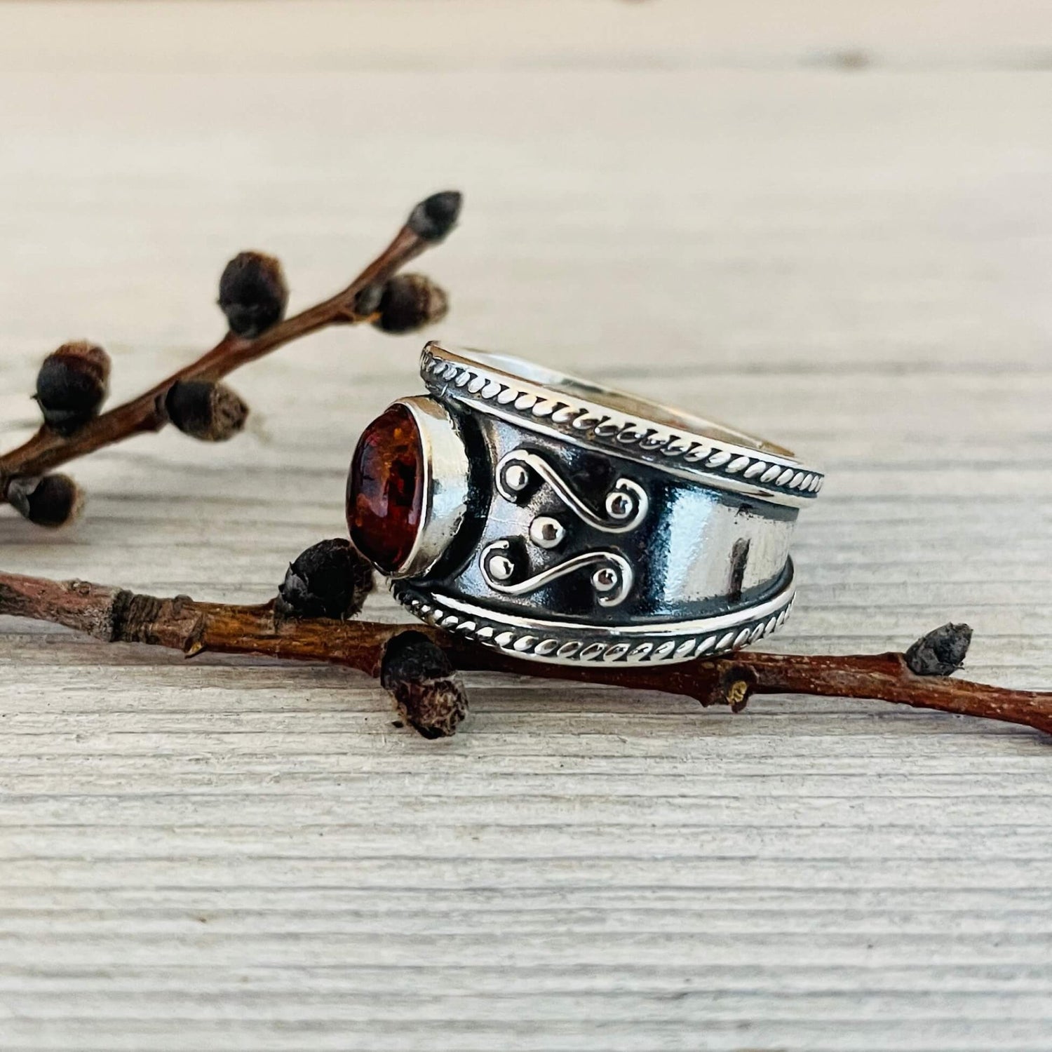oval shaped amber stone set in a wide sterling silver band