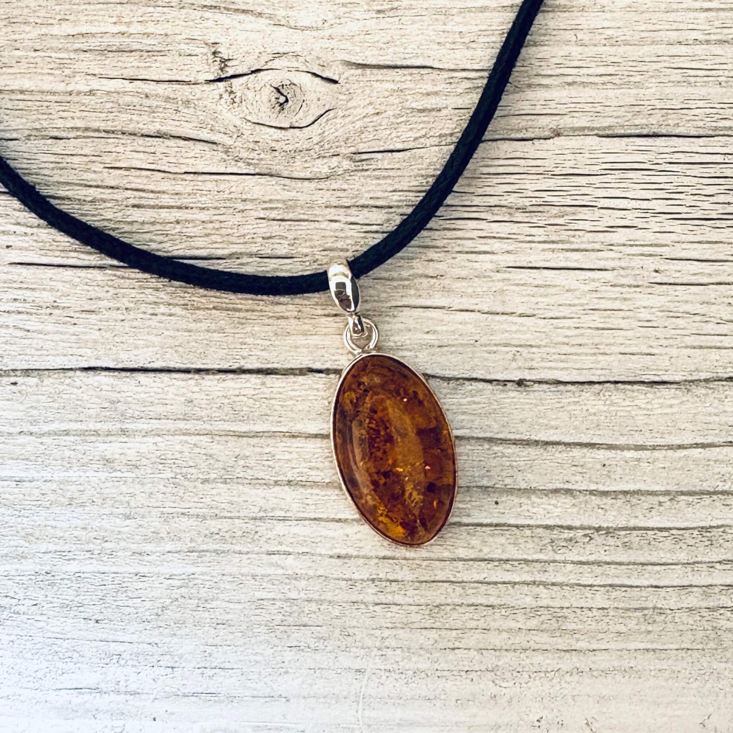 oval shaped cognac amber pendant set in sterling silver front side