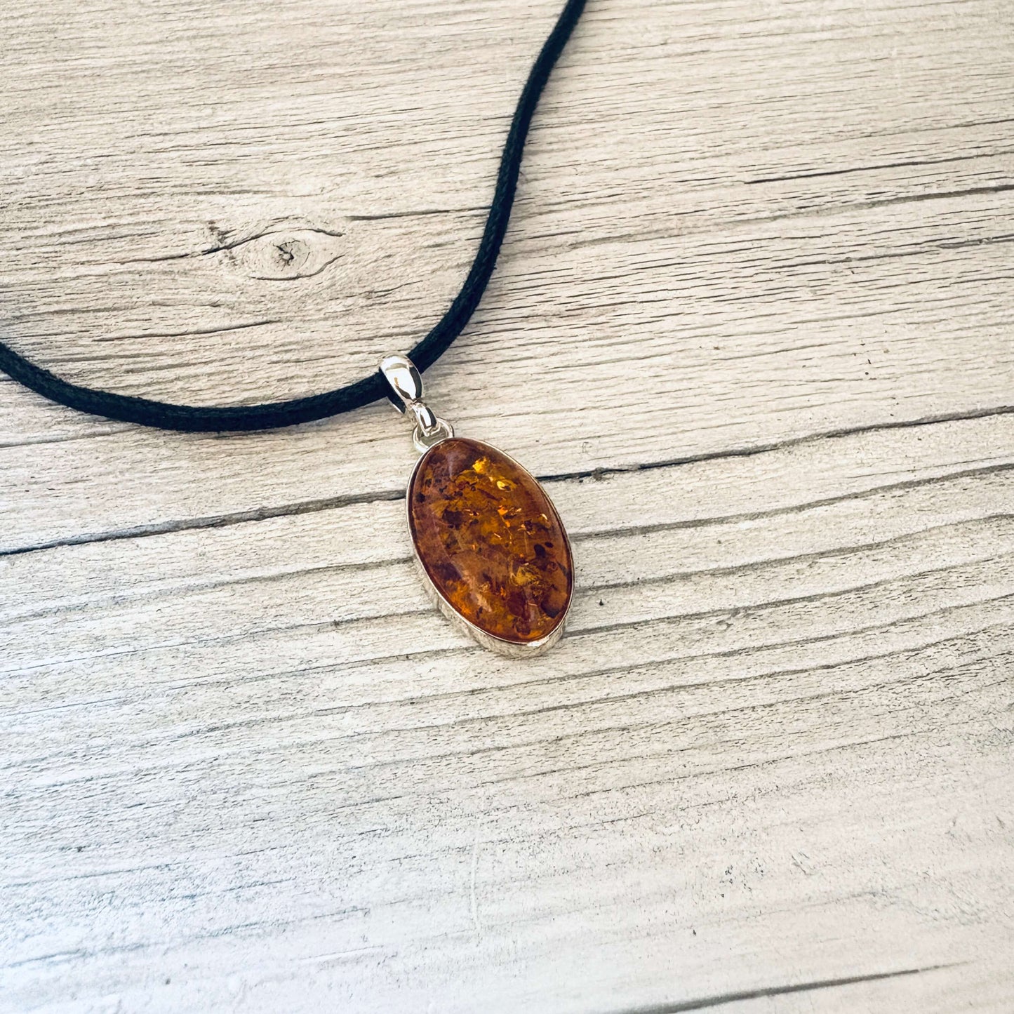 oval shaped cognac amber pendant set in sterling silver with a bail