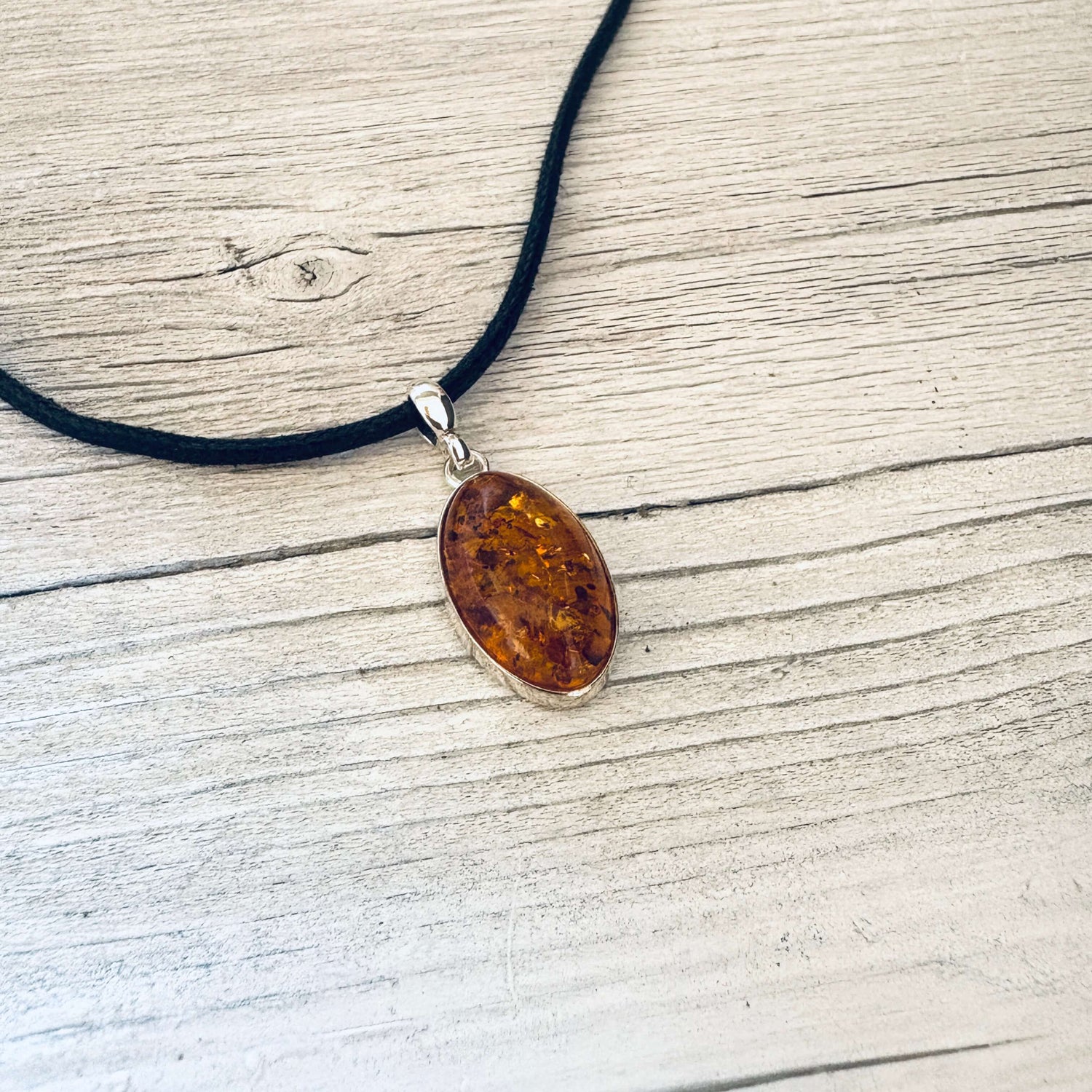 oval shaped cognac amber pendant set in sterling silver with a bail