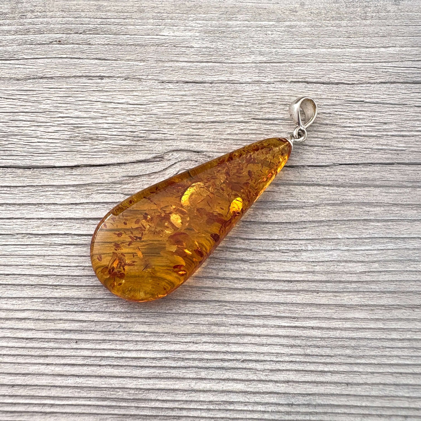 Teardrop-shaped amber pendant on with a sterling silver bail