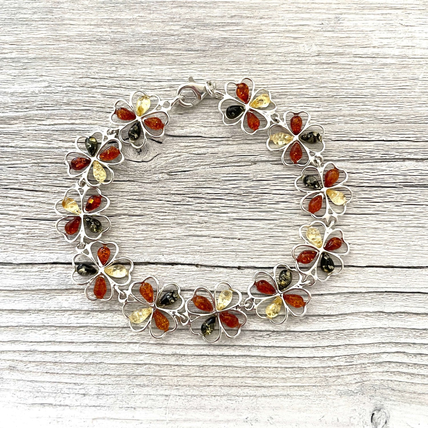 sterling silver flower shaped bracelet with cognac, green and honey amber stones.