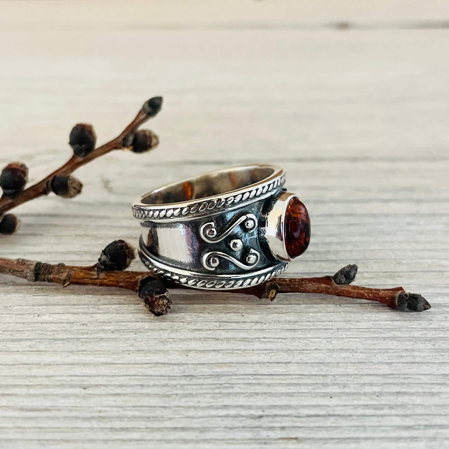 oval shaped amber stone set in a wide sterling silver band right side