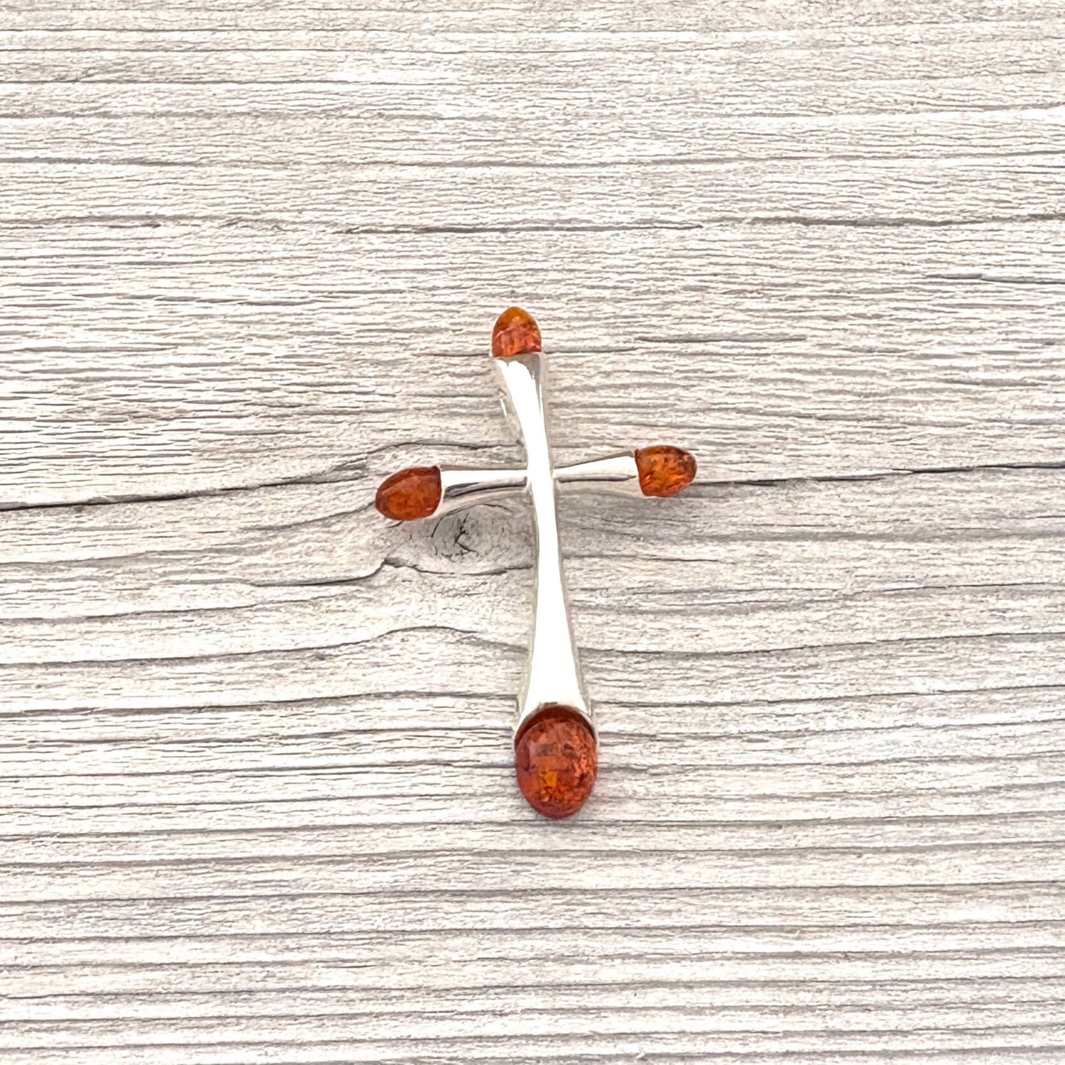 Silver earrings with amber drops on a wooden surface