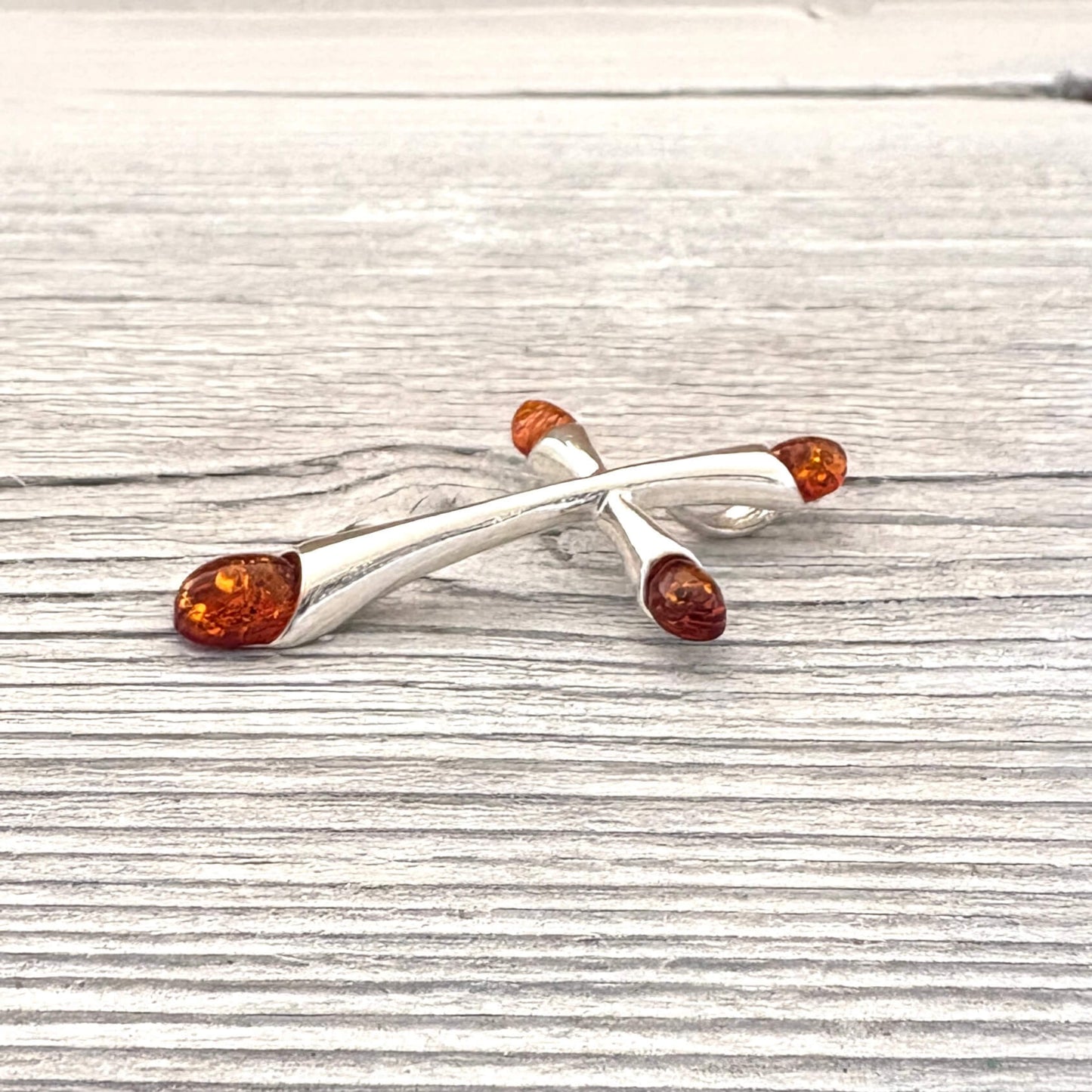 Silver brooch with amber stones on a wooden surface