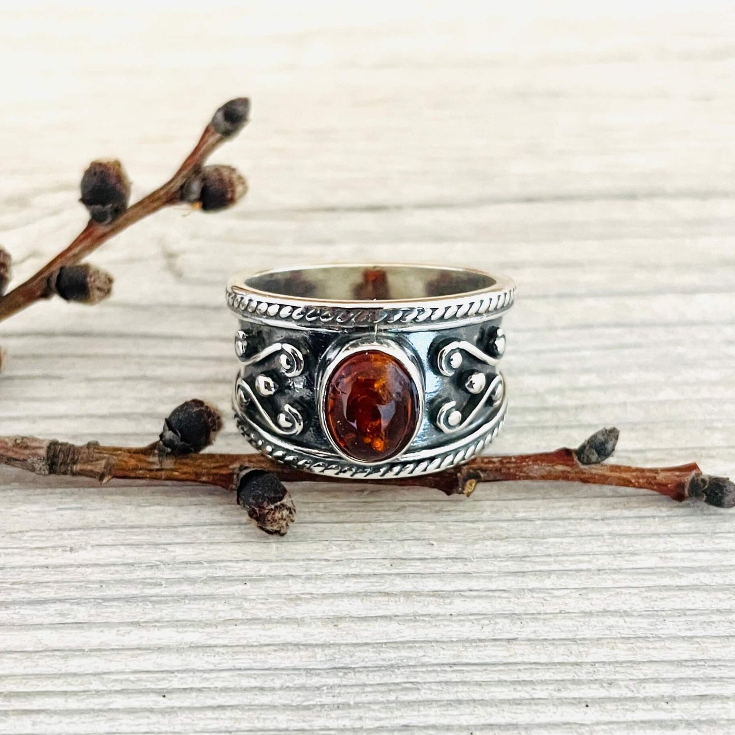 oval shaped amber stone set in a wide sterling silver band