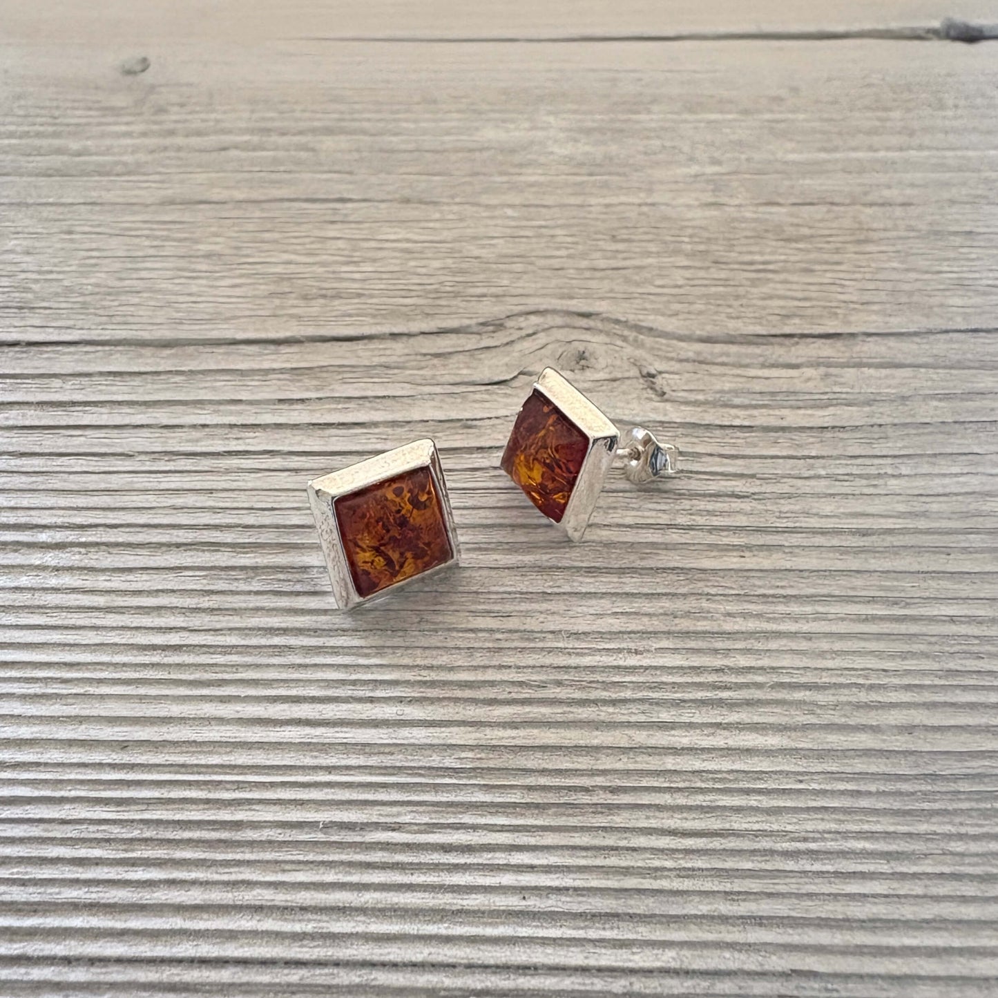 Square amber stud earrings on a wooden surface