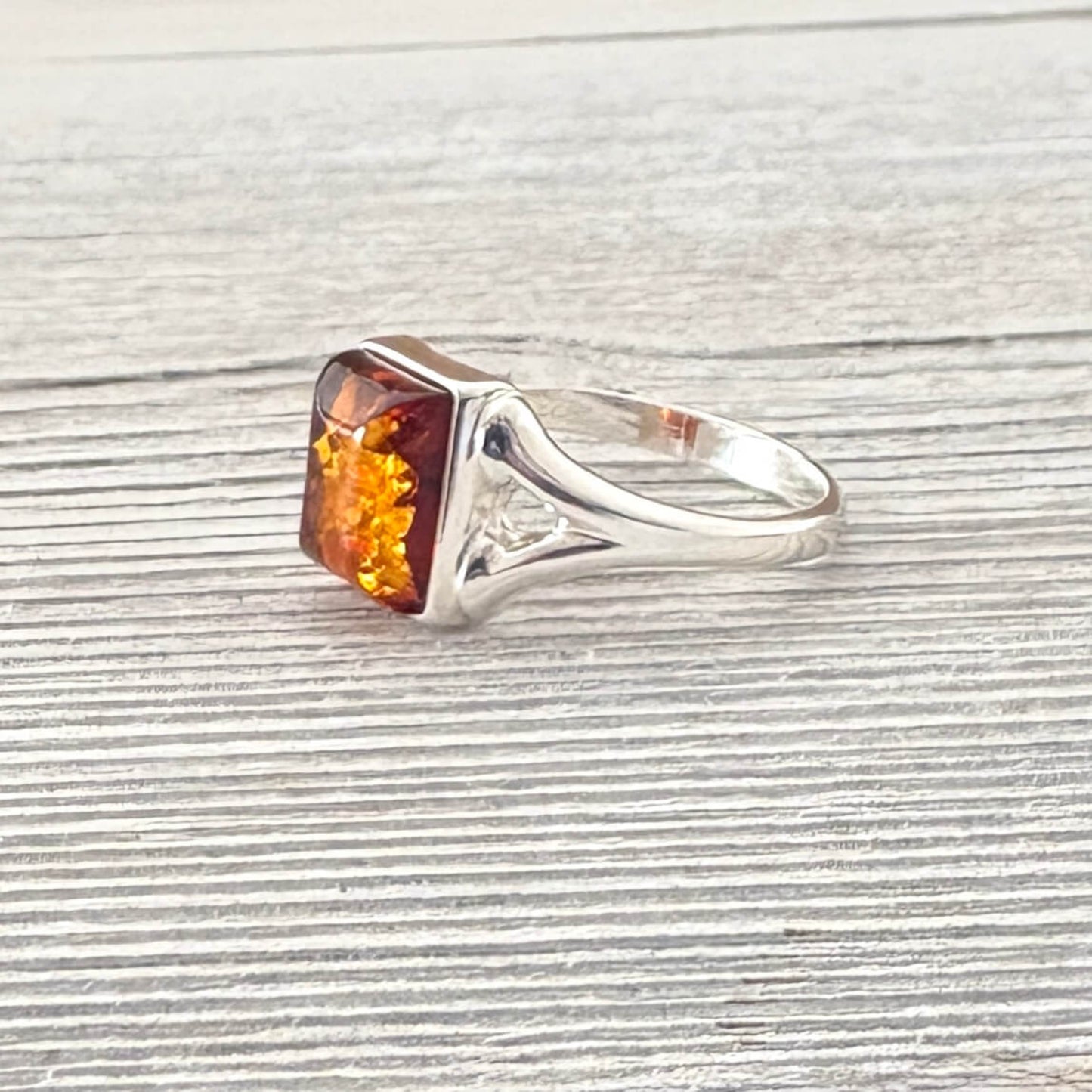 Silver ring with a square-cut amber stone on a textured gray surface