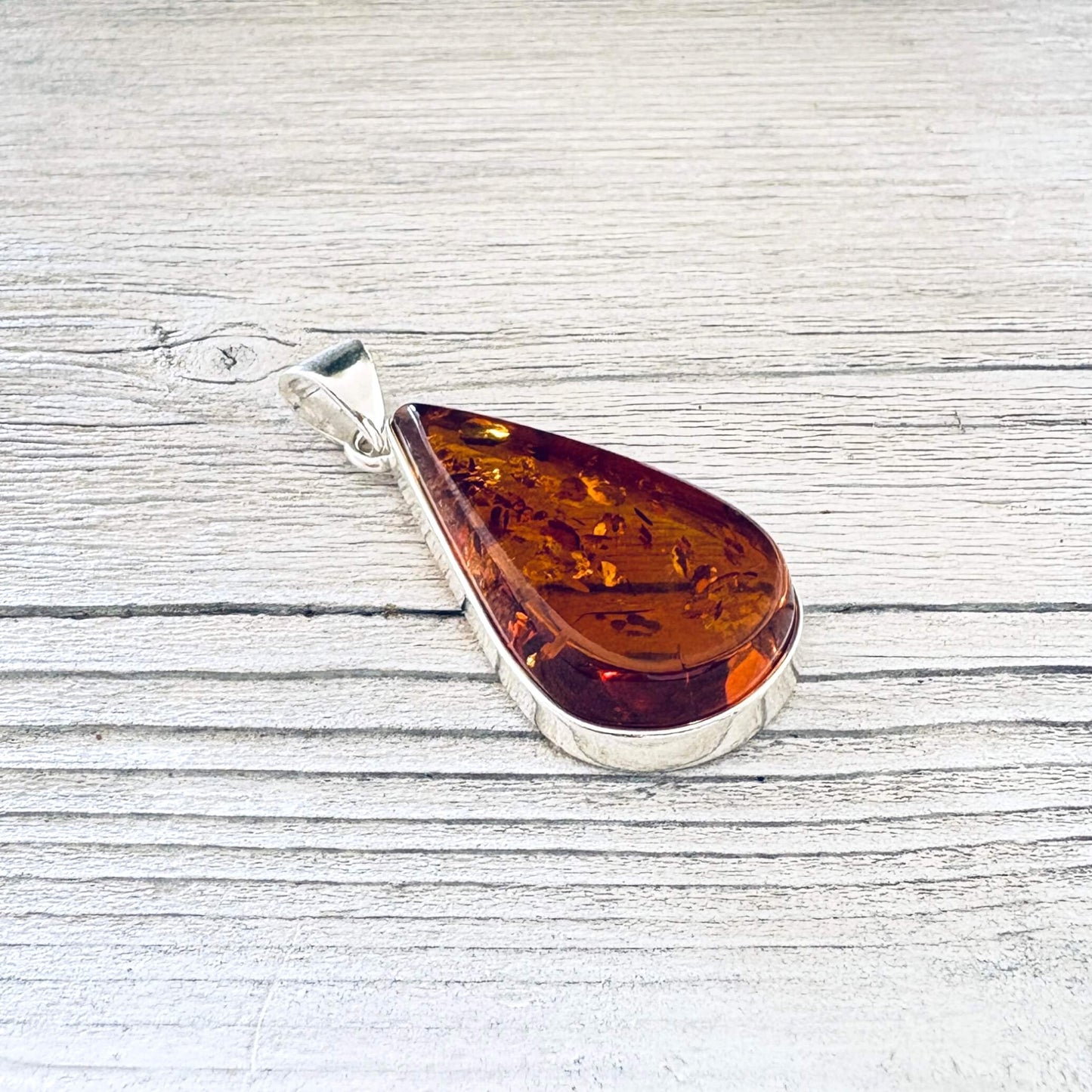 A teardrop-shaped amber pendant with a polished silver bail.