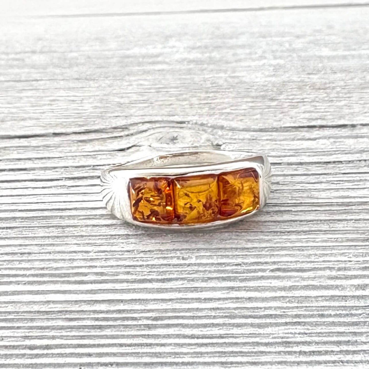 Silver ring with amber stones on a wooden surface