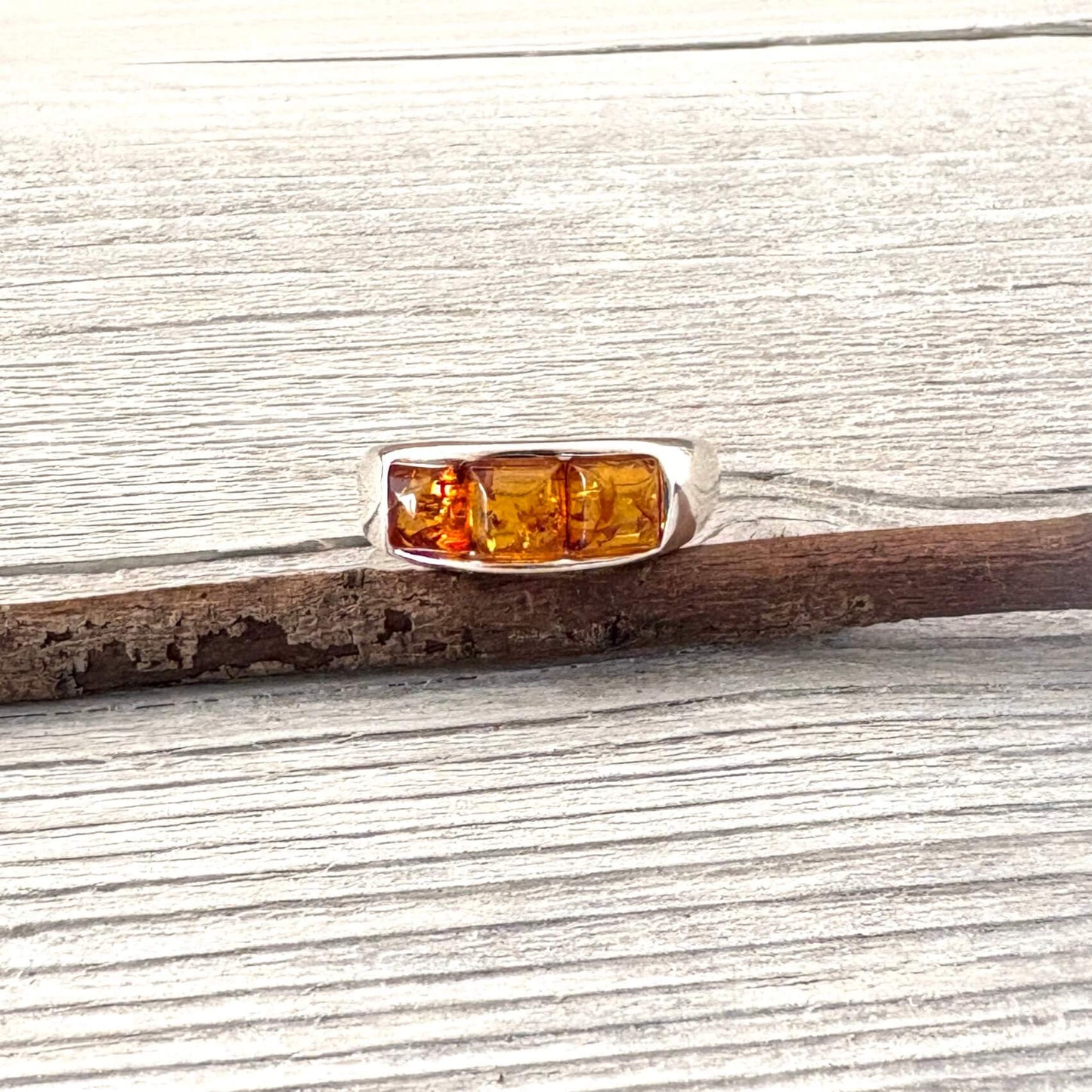 Silver ring with amber stones on a wooden surface