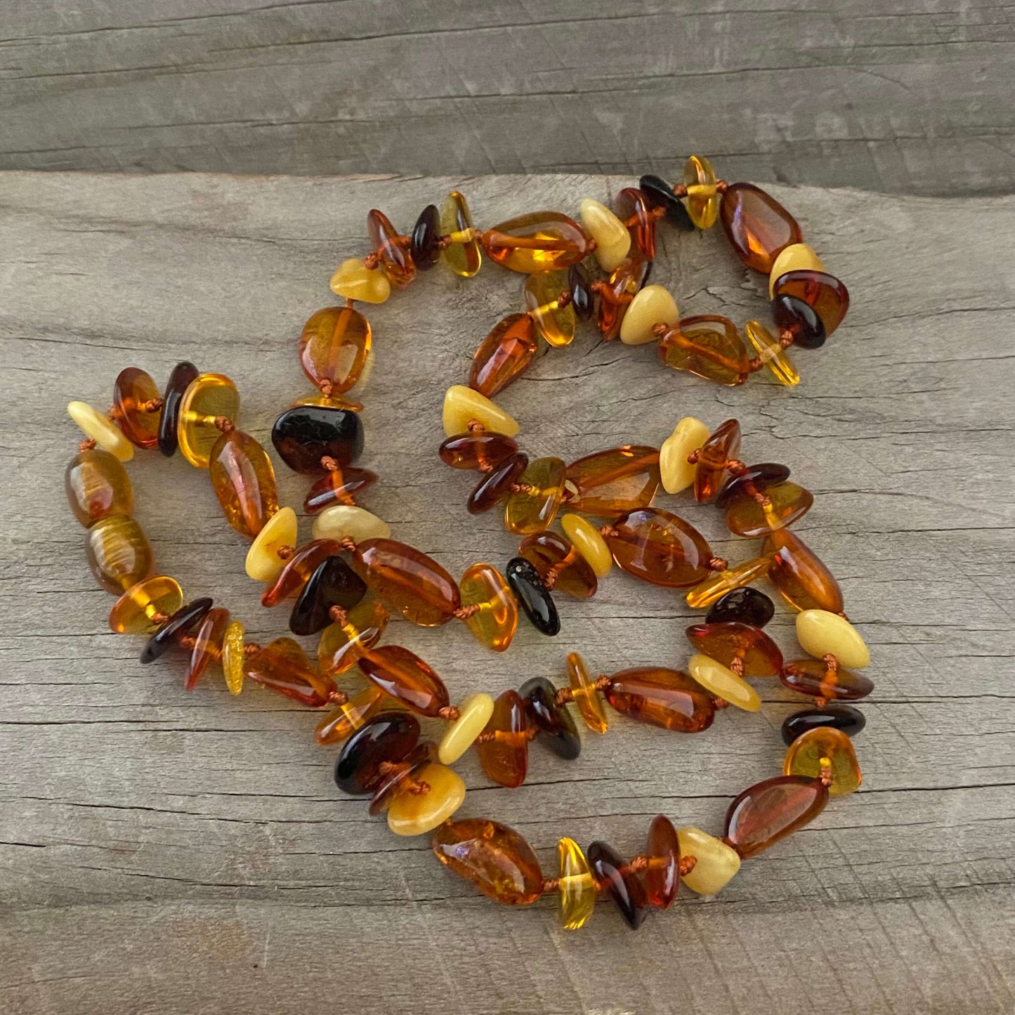Close up of polished Baltic amber necklace beads showing their varied colours, shapes and natural patterns.