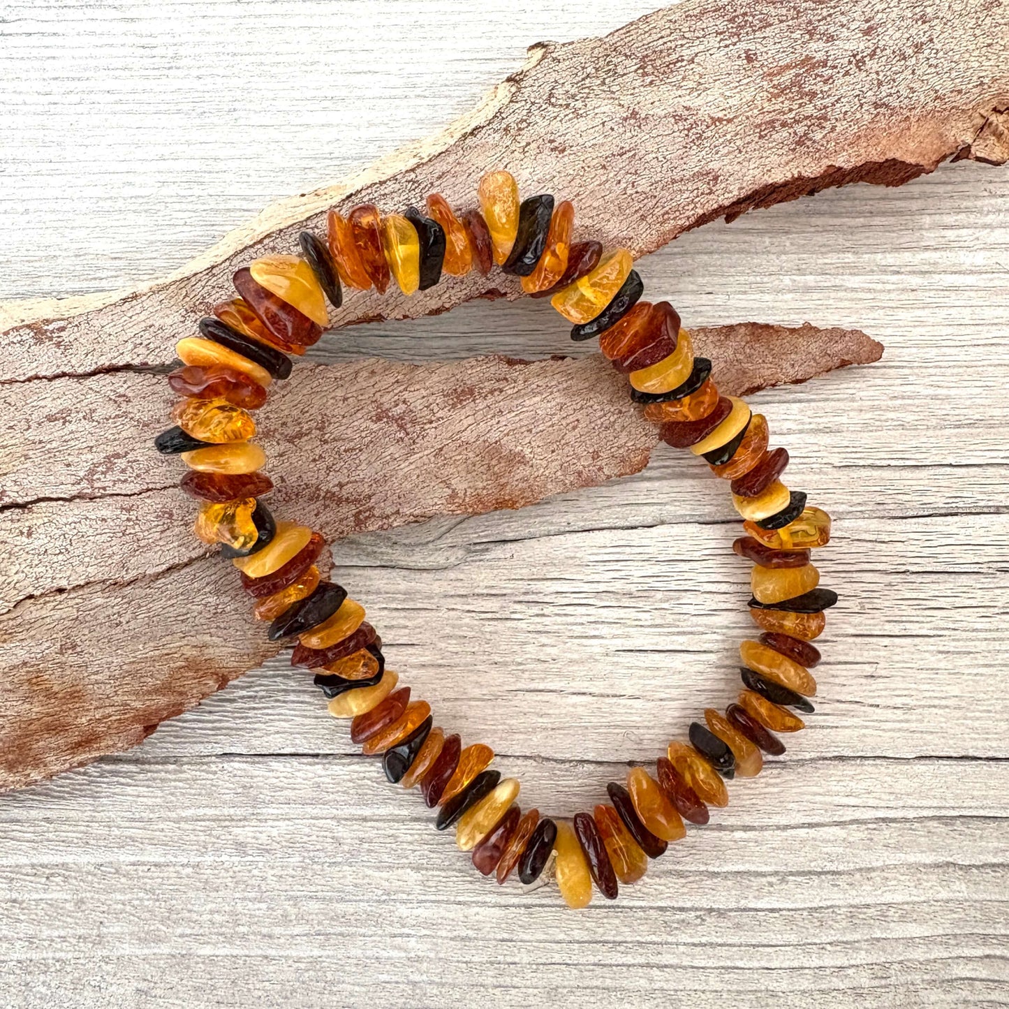 Multicolored amber bead bracelet on a wooden surface