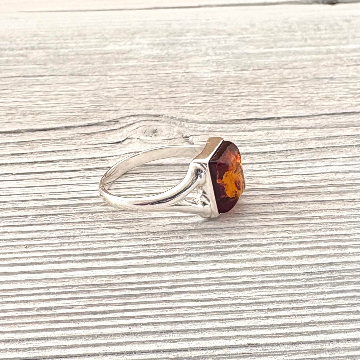 Silver ring with a amber stone on a wooden surface