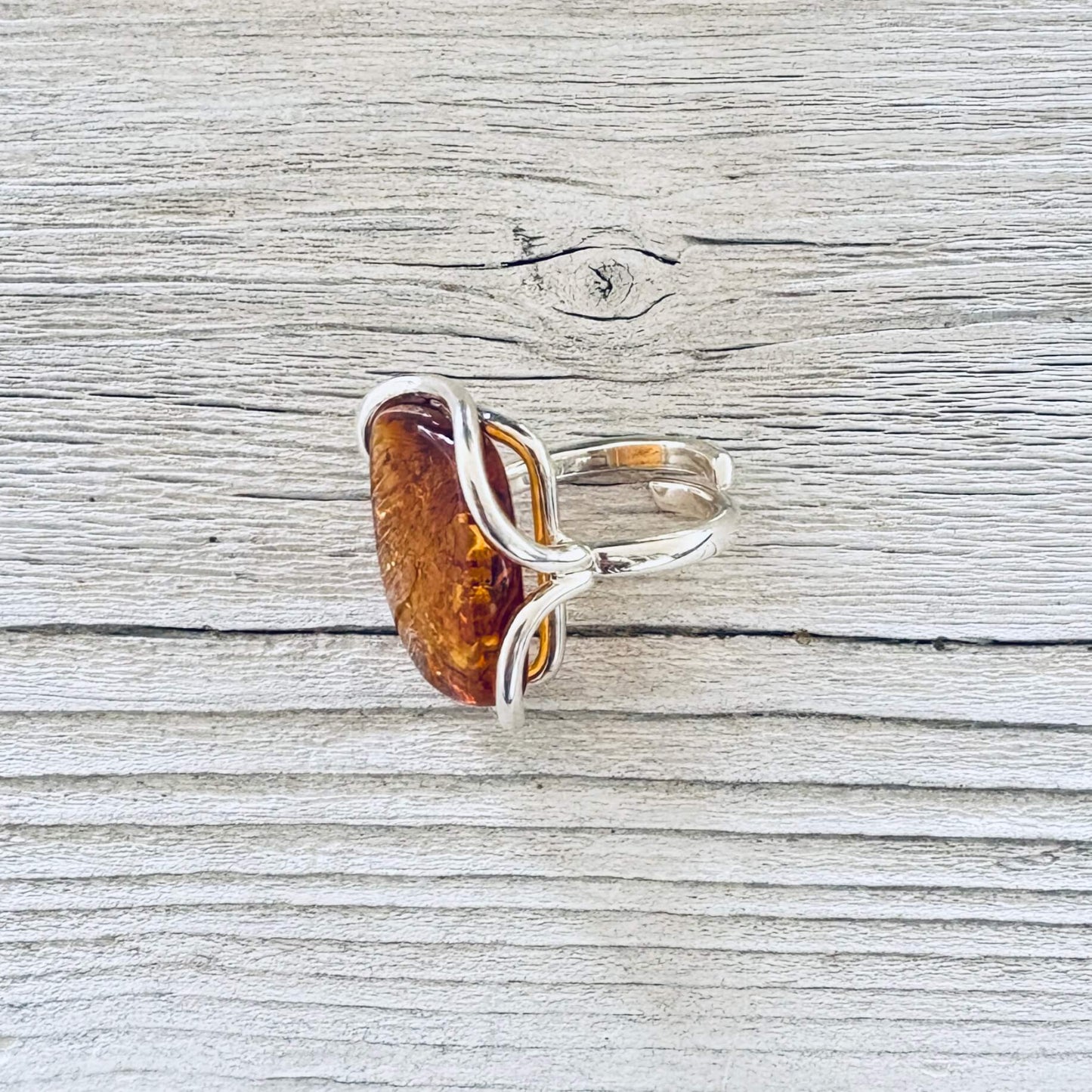 A silver ring featuring a large, polished amber-colored stone.