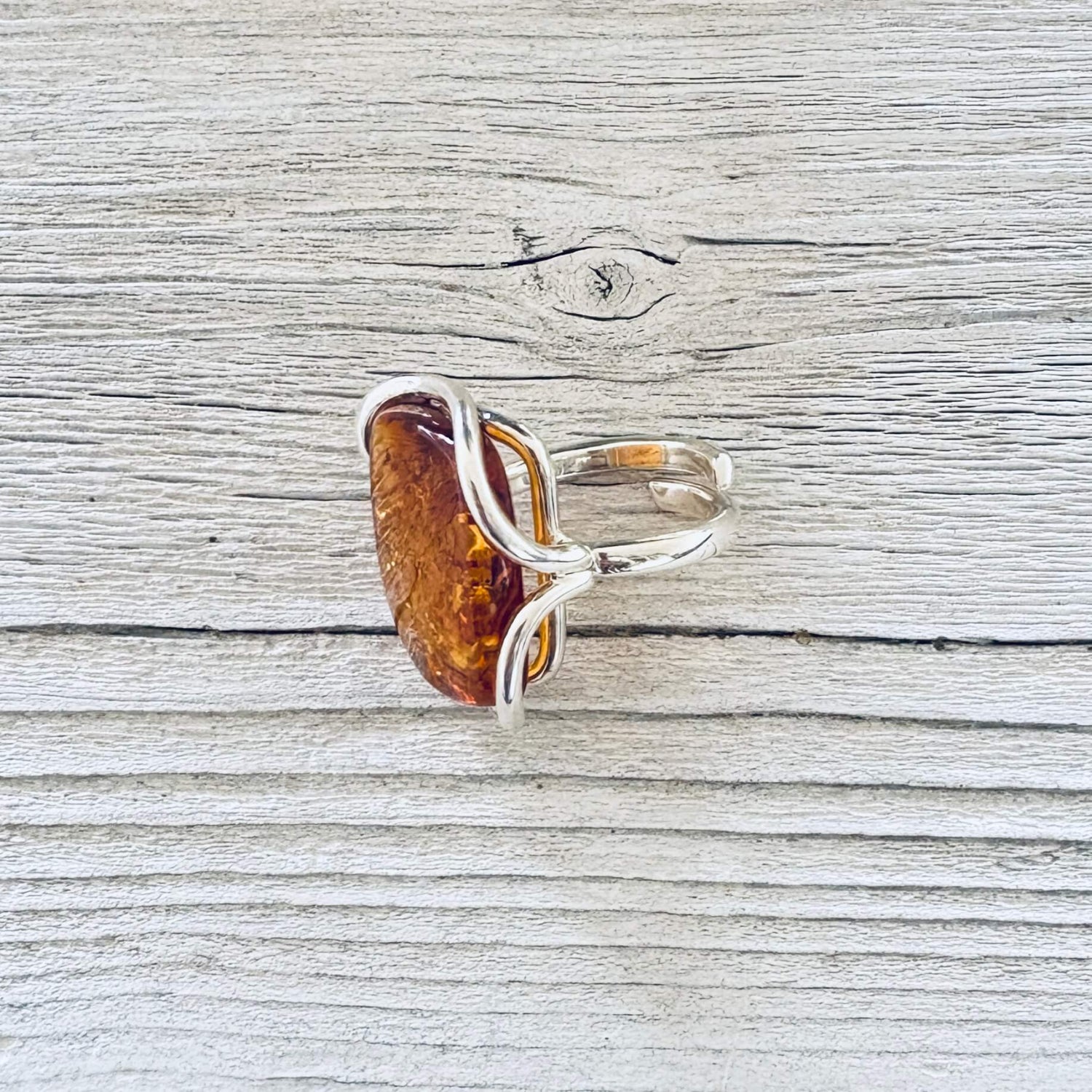 A silver ring featuring a large, polished amber-colored stone.