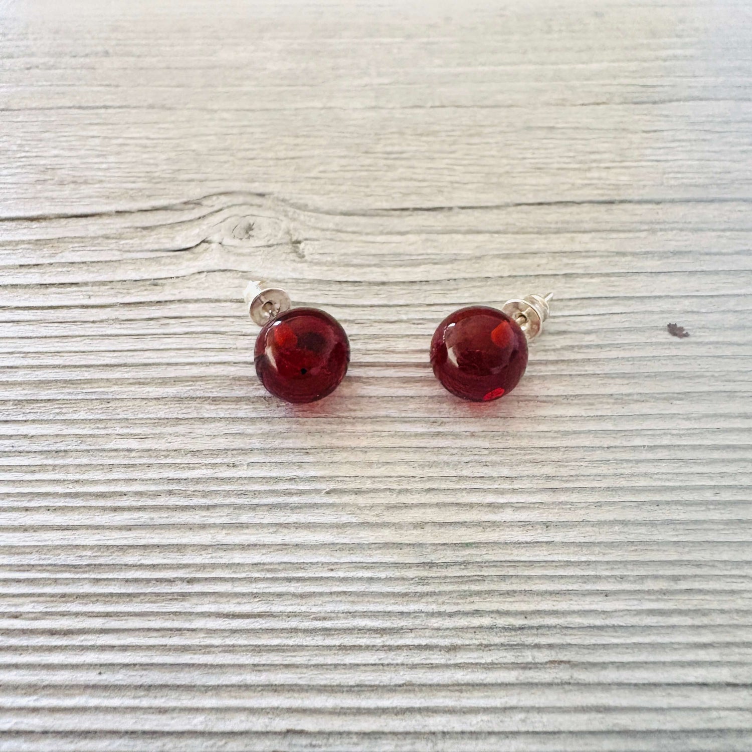 Pair of cognac stud earrings on a light wooden surface