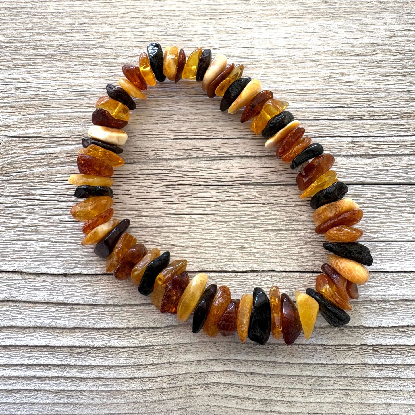 Genuine multicolored amber bracelet on a wooden surface