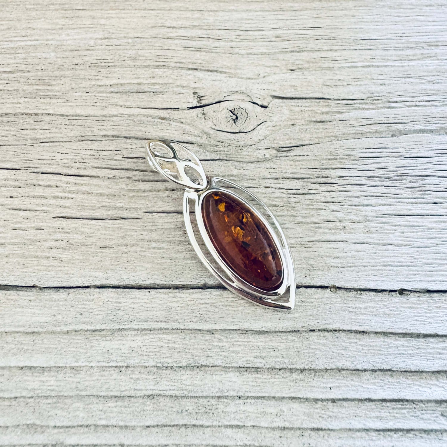 Angled view of cognac amber pendant showing the marquise silver setting 