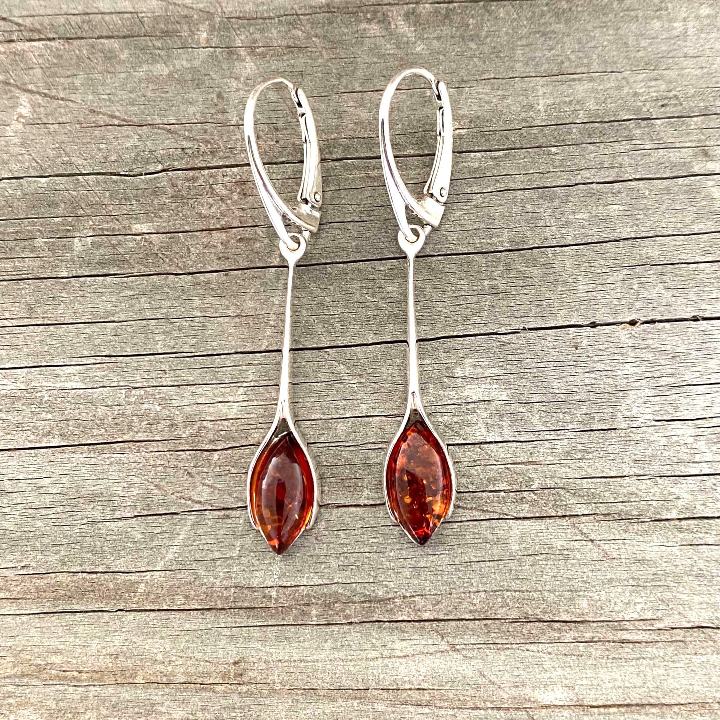 Pair of silver earrings with amber stones on a wooden surface