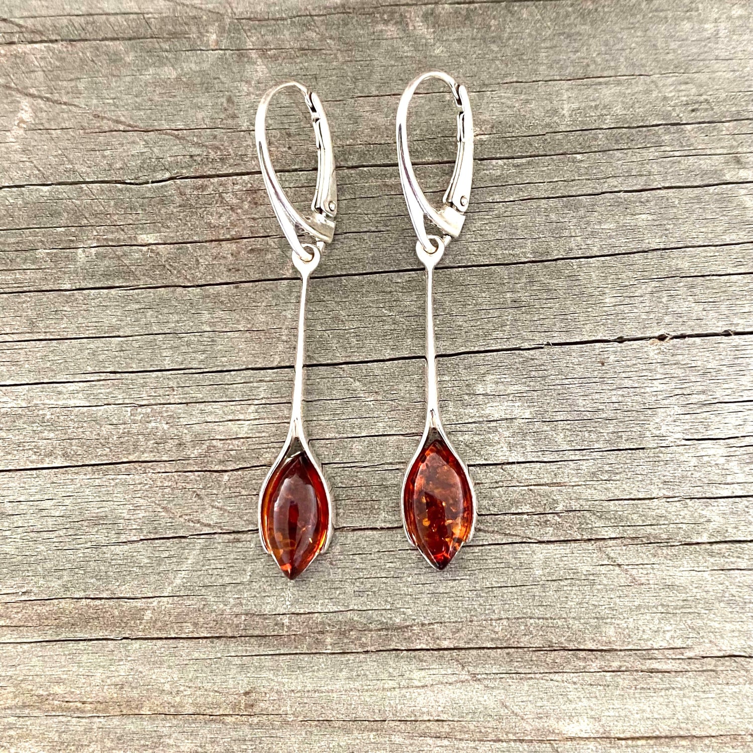 Pair of silver earrings with amber stones on a wooden surface