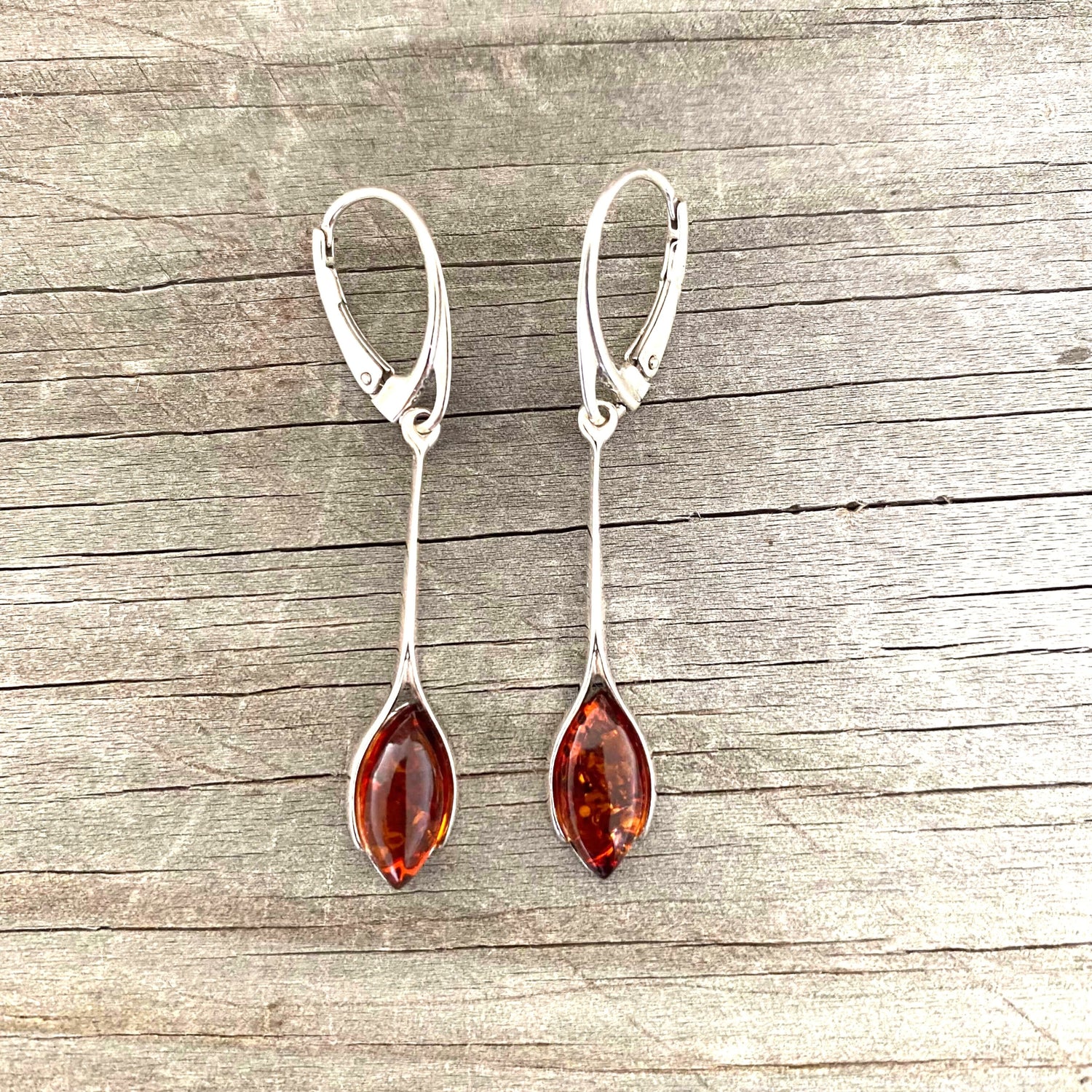 Pair of silver earrings with amber stones on a wooden surface