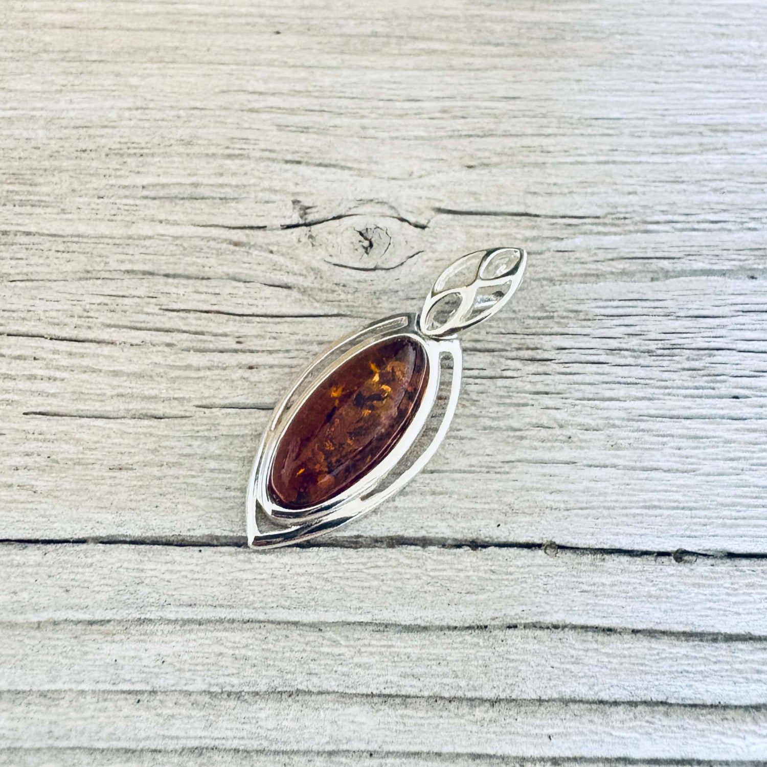 Cognac Baltic amber pendant with oval stone, set in a silver marquise frame and a leaf inspired silver bail.