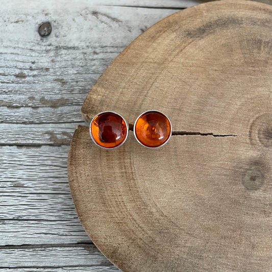 Round amber stud earrings on a wooden surface