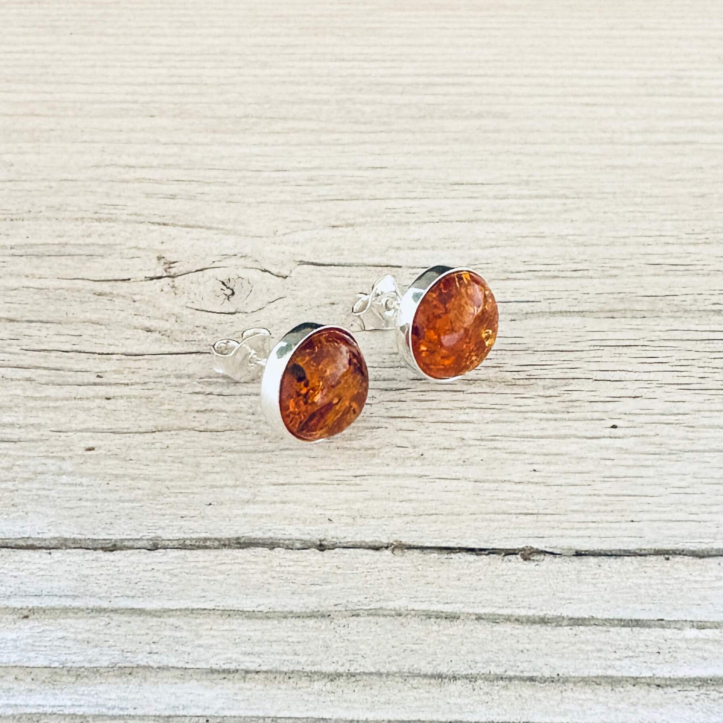 Angled view of round cognac amber stud earrings 