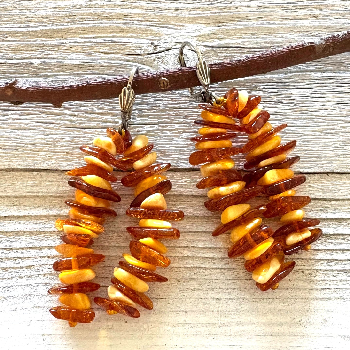 Pair of long amber earrings on a wooden surface