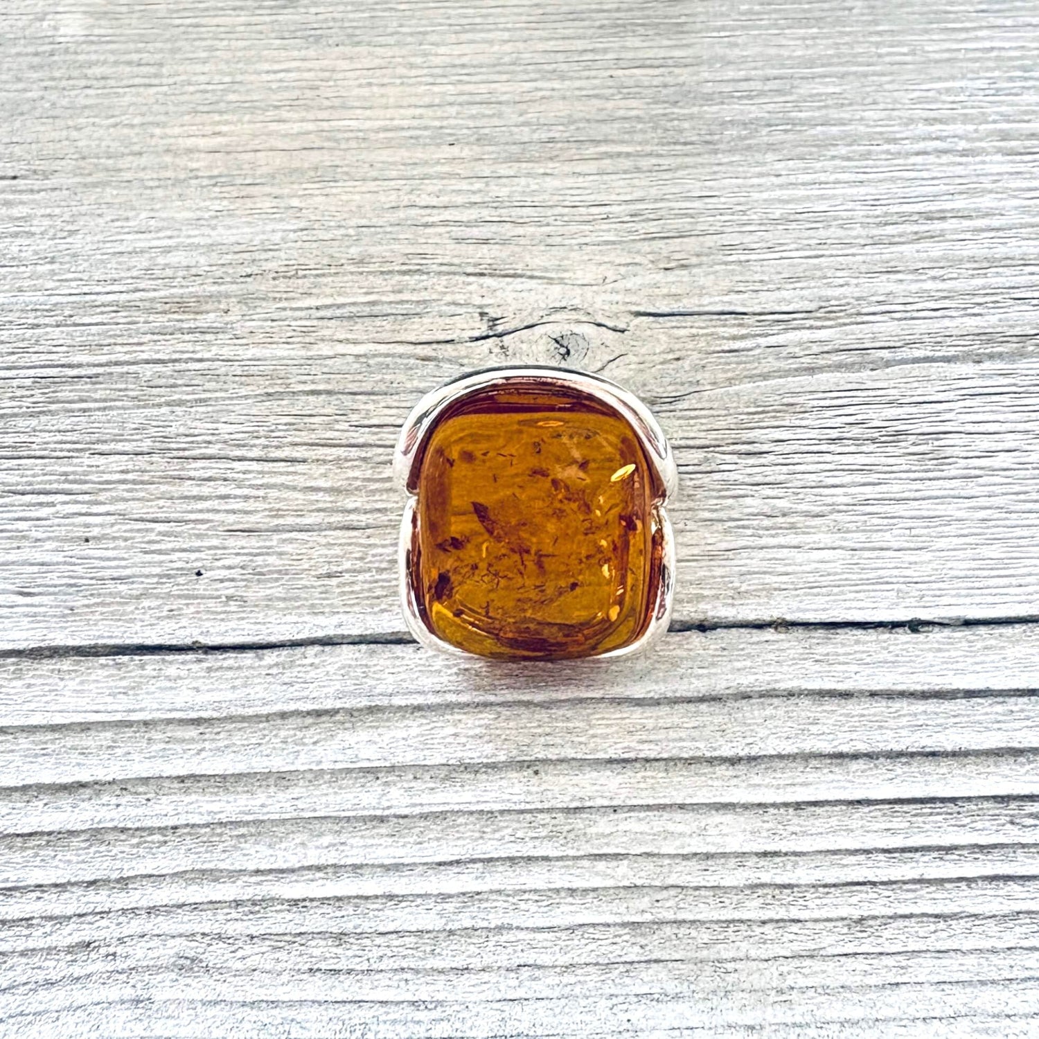 Genuine cognac amber sterling silver ring with natural inclusions, front view.