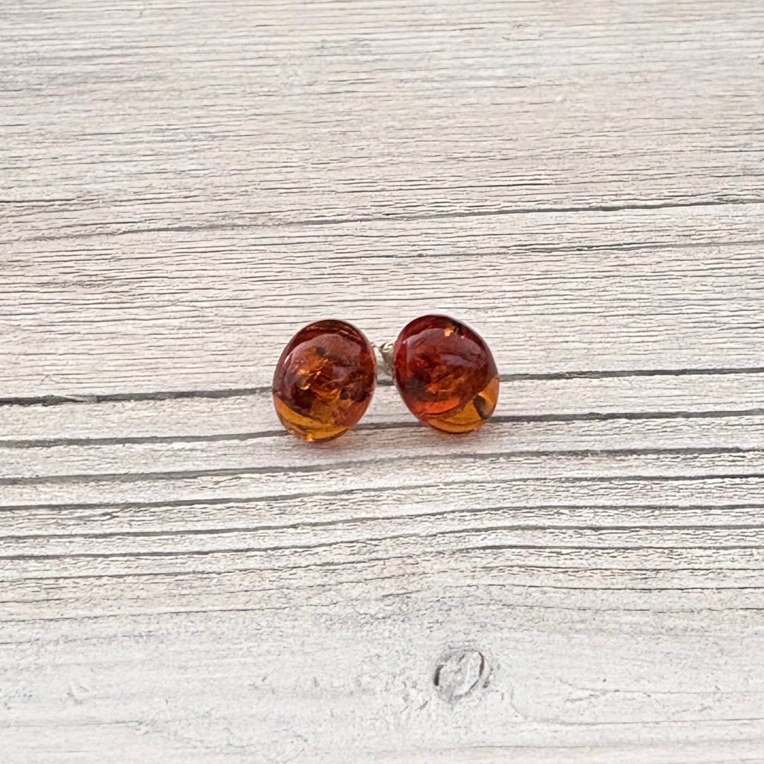 Oval amber stud earrings on a light wooden surface