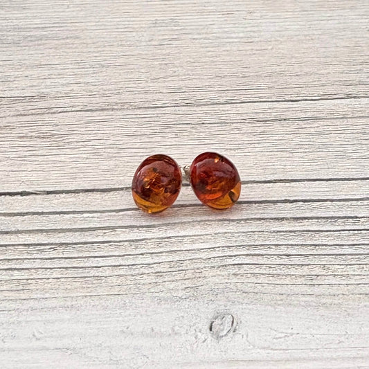Oval amber stud earrings on a light wooden surface