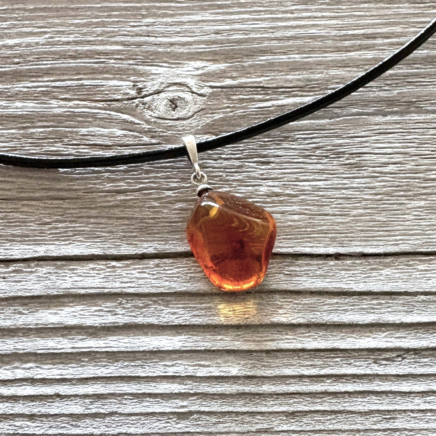 Polished amber cognac pendant on a black leather strap