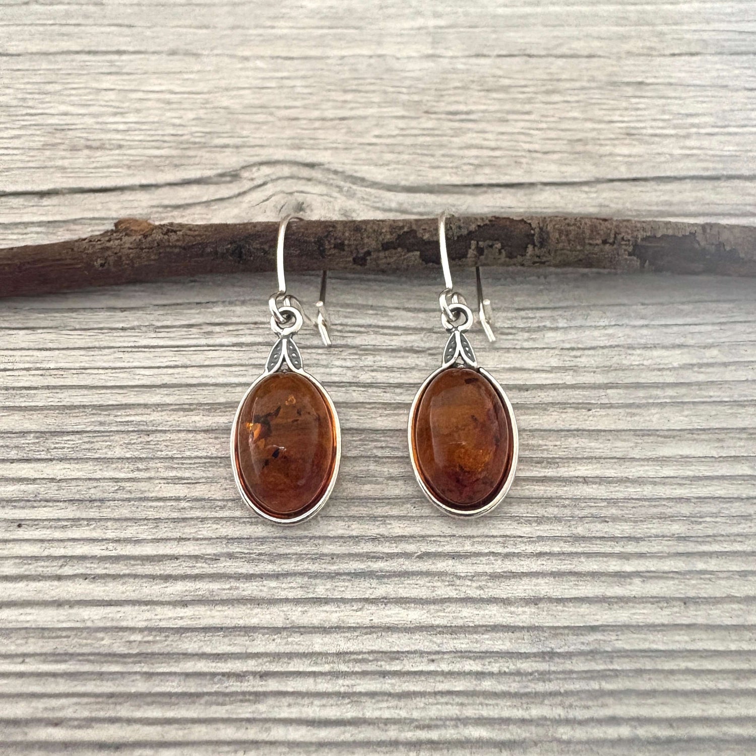 Pair of amber teardrop earrings on a wooden surface
