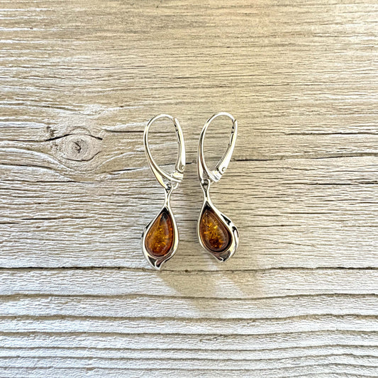 Cognac Baltic amber teardrop earrings framed by sculpted silver curves with elegant leverback hooks.