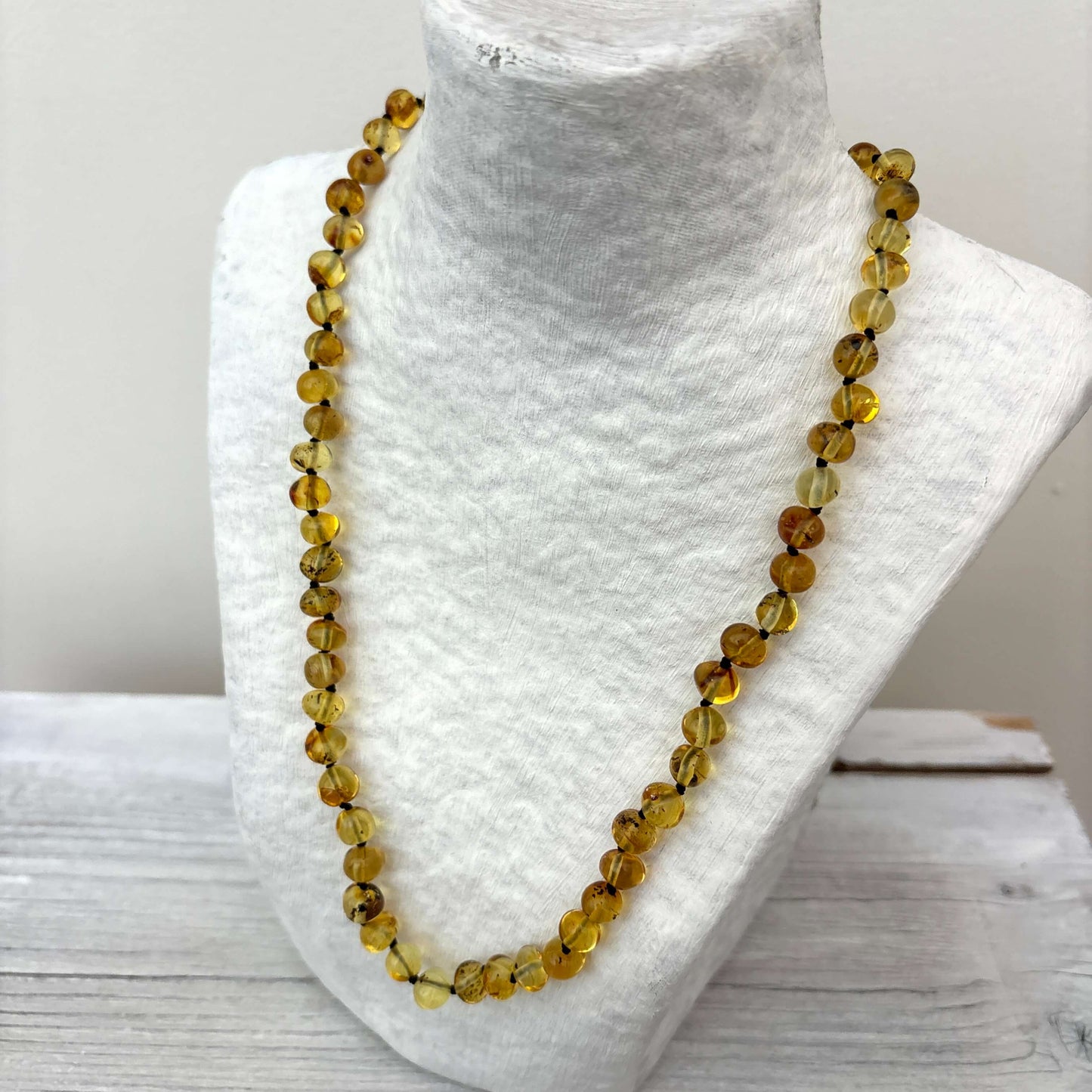 Light green deaded necklace on a mannequin bust with a white background
