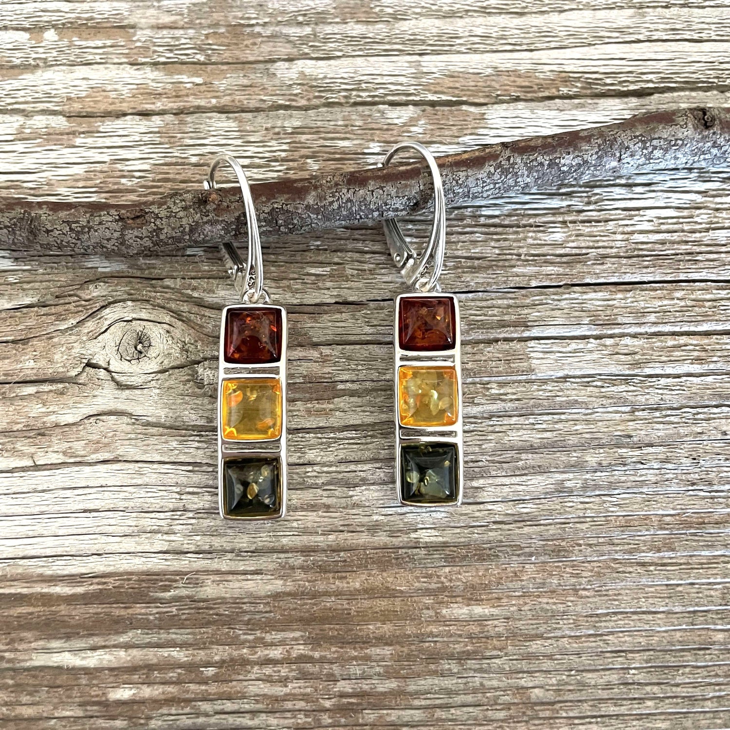 A pair of silver drop earrings with three stacked rectangular gemstones on each earring.