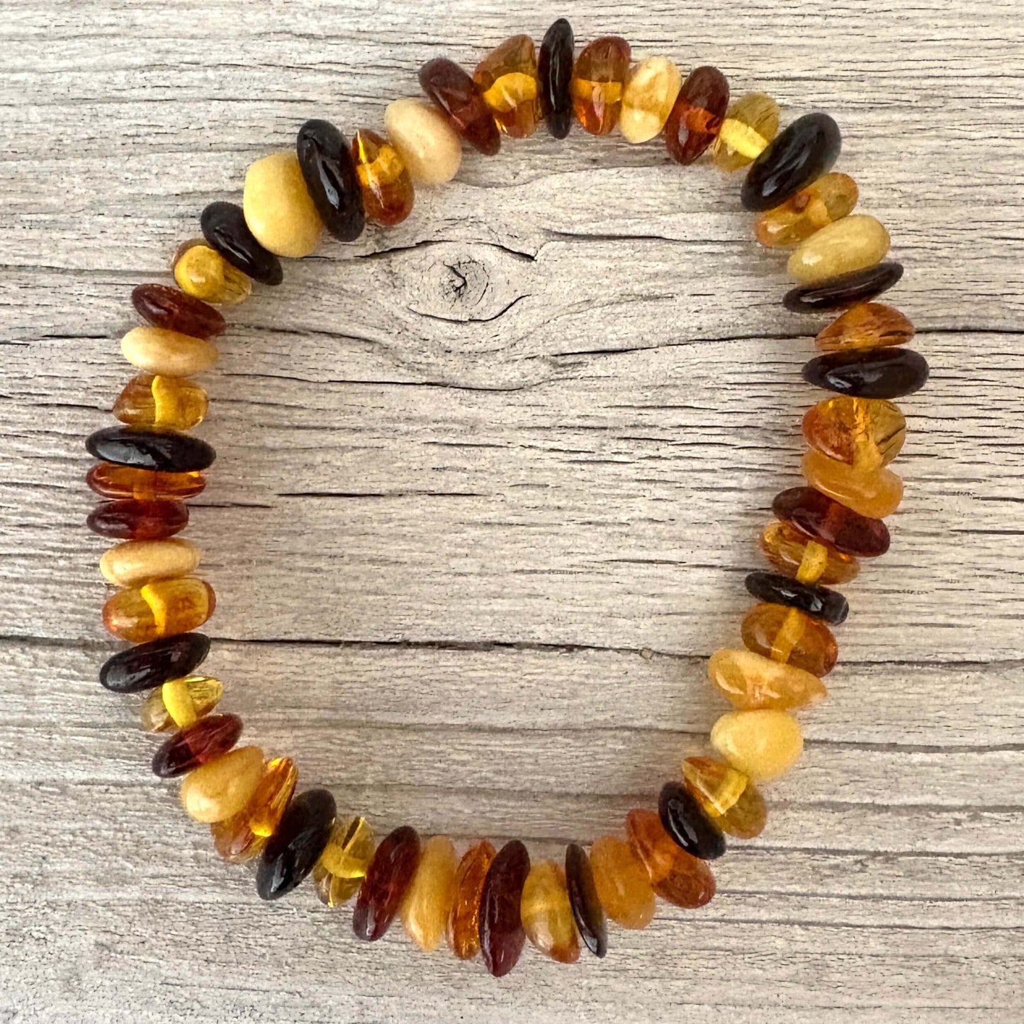 Multicolored beaded amber bracelet on a wooden surface