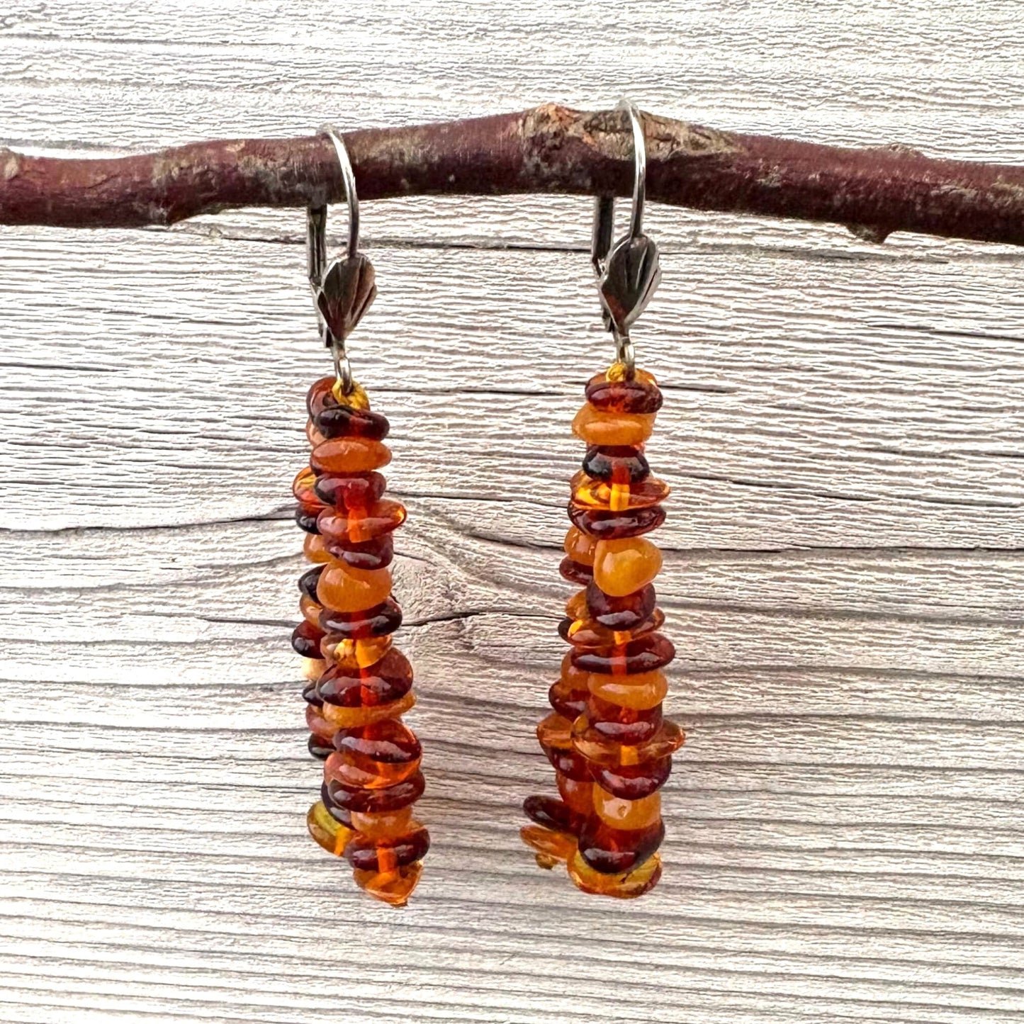 Pair of long amber beaded earrings on a wooden branch