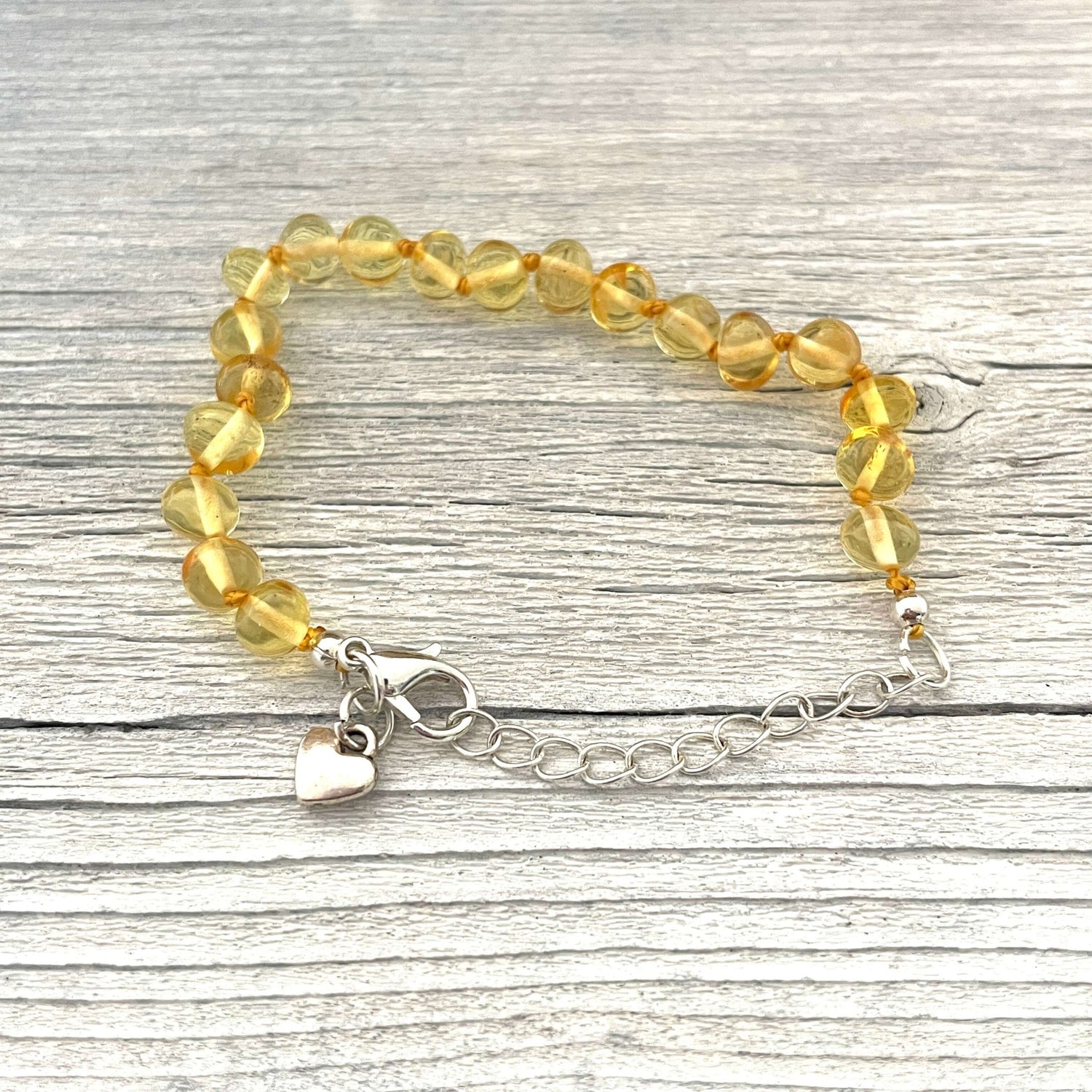 silver love heart charm on a round beaded amber bracelet