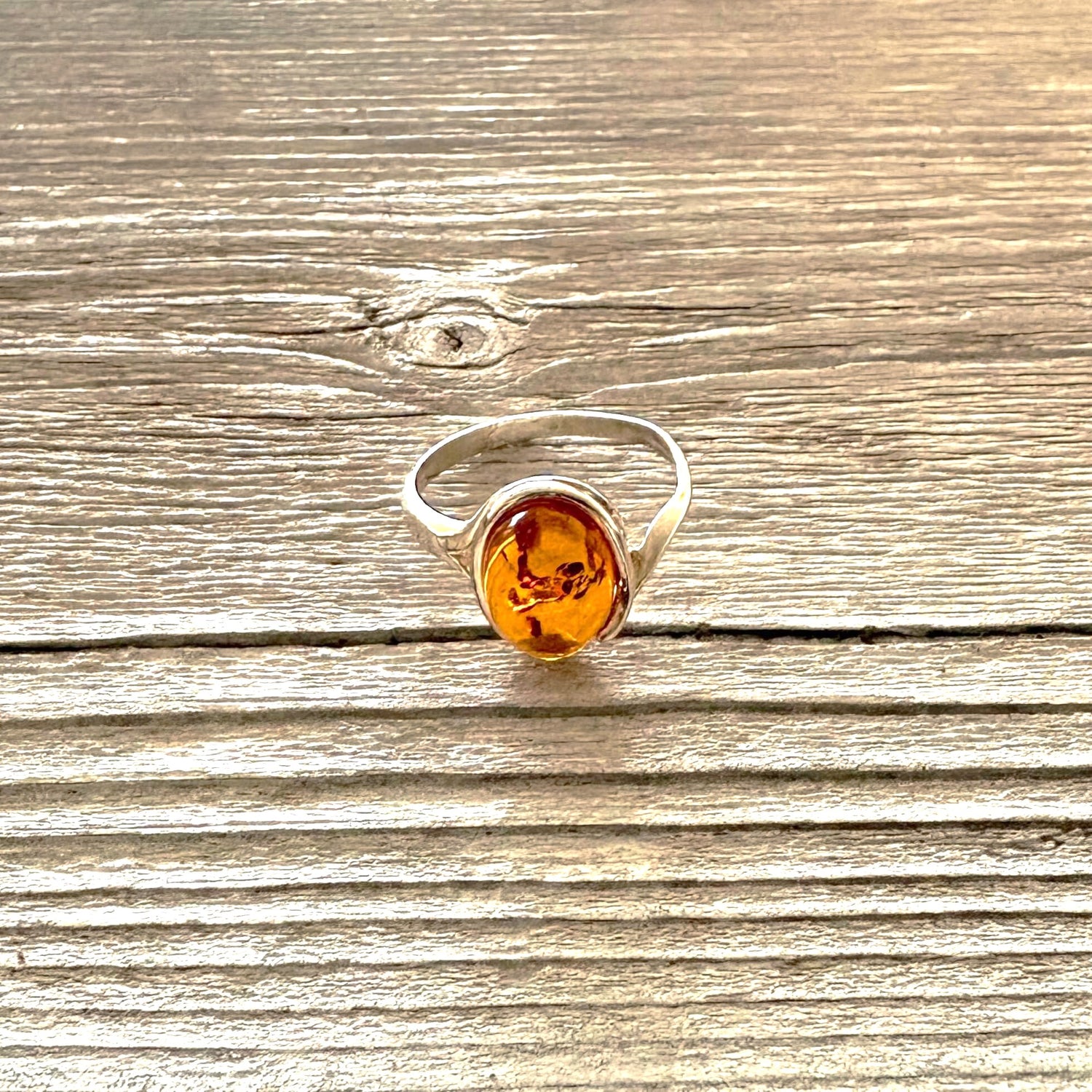 Silver ring with a amber stone on a wooden surface