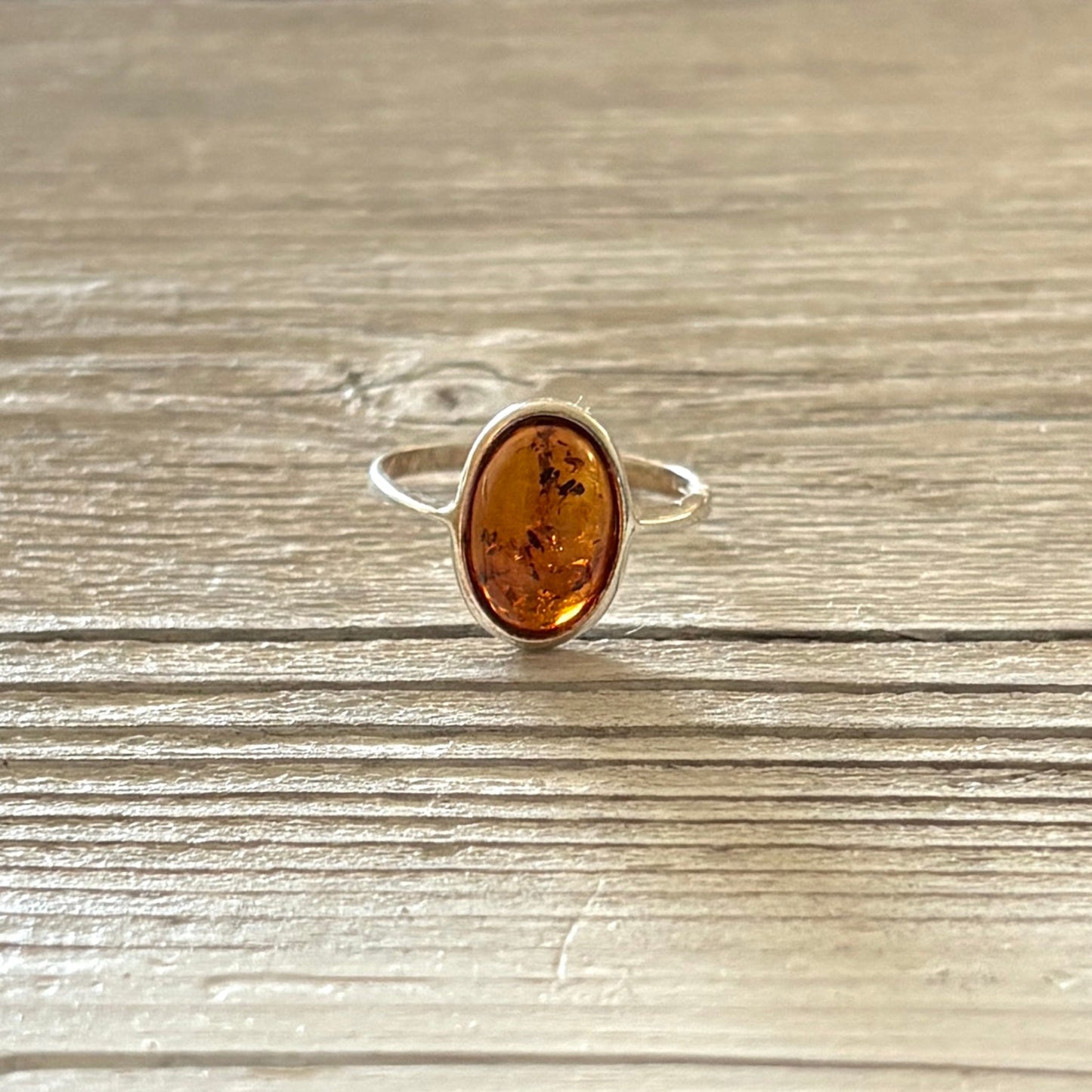 Silver ring with a amber stone on a wooden surface