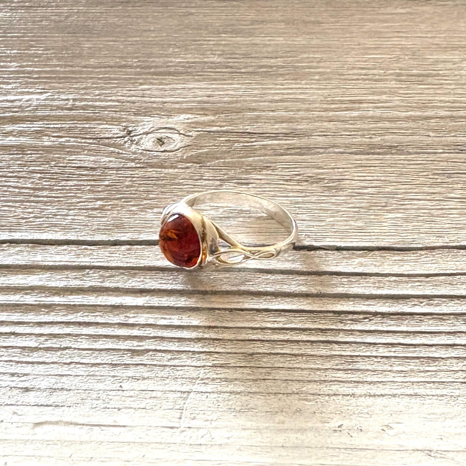 Siver ring with a amber stone on a wooden surface