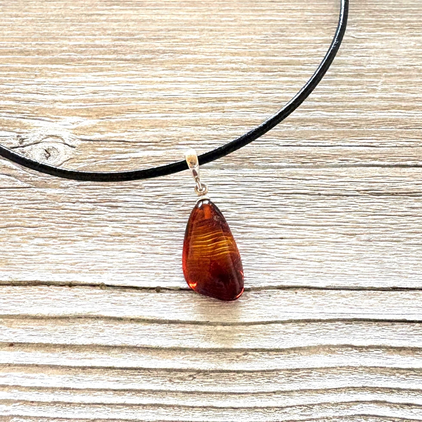 Necklace with a teardrop-shaped amber pendant on a wooden surface